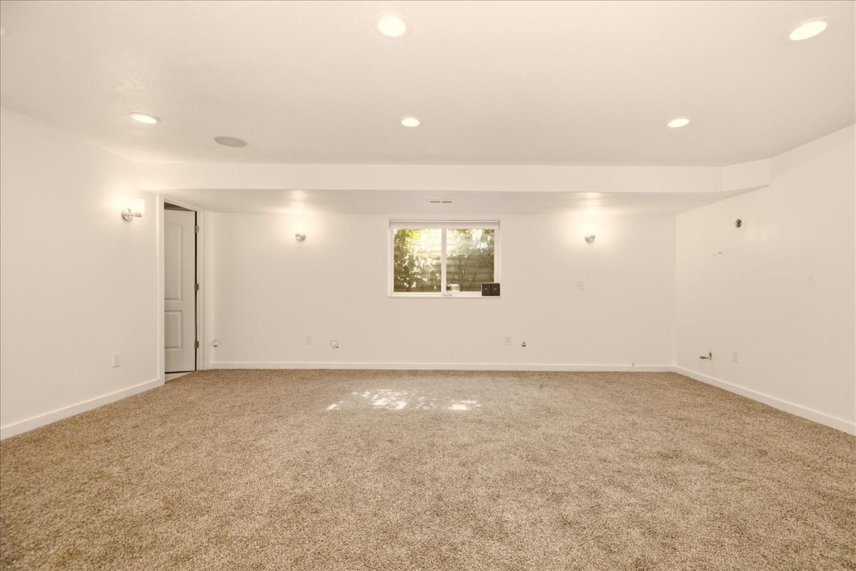 Carpeted room featuring recessed lighting, a window with exterior greenery, and wall sconces