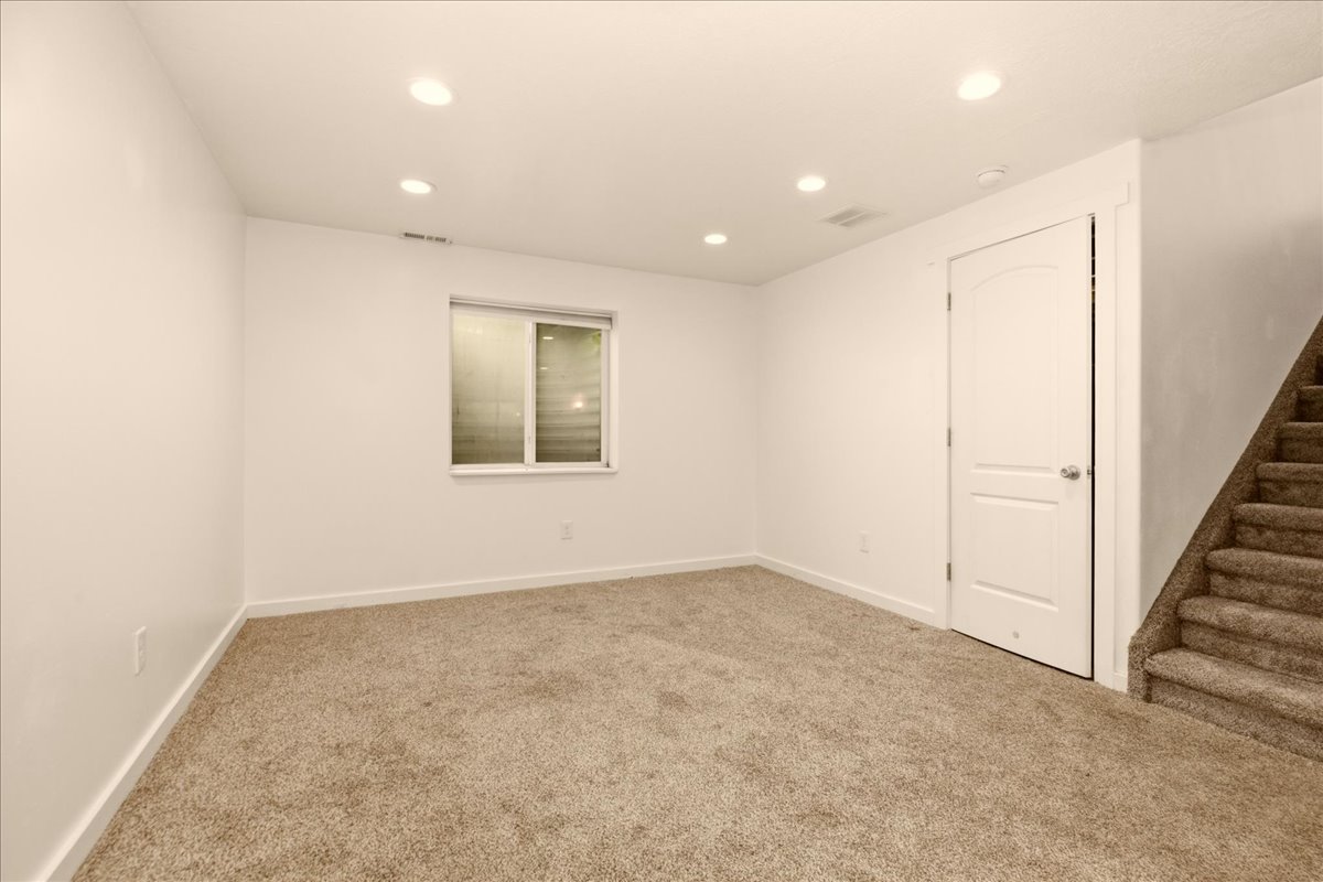 Carpeted room with recessed lighting, white walls, and a window with blinds