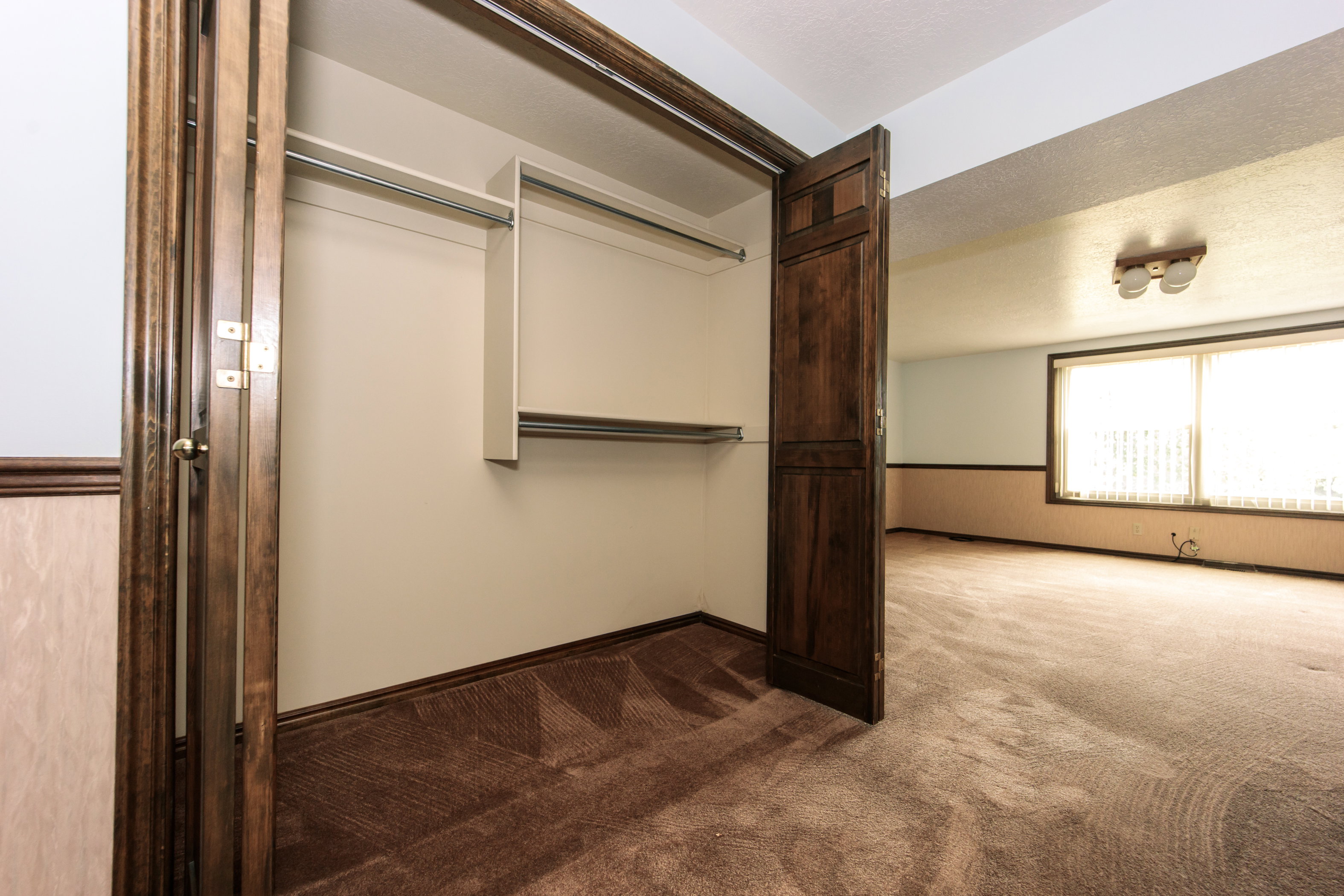 Built-in closet with bifold doors, featuring a multi-tiered hanging system and upper shelving
