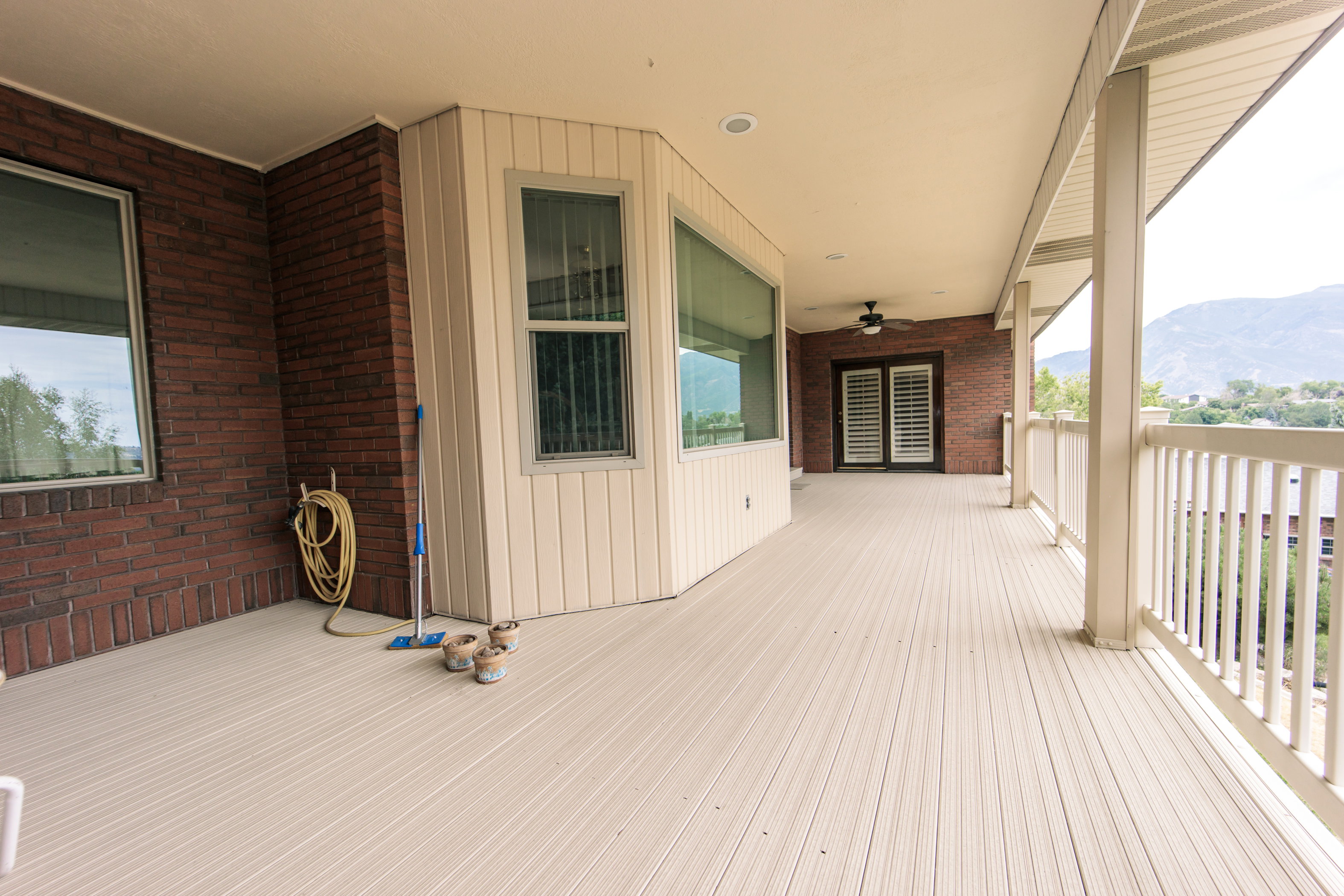 Expansive covered deck featuring composite decking, white railing, and a ceiling fan