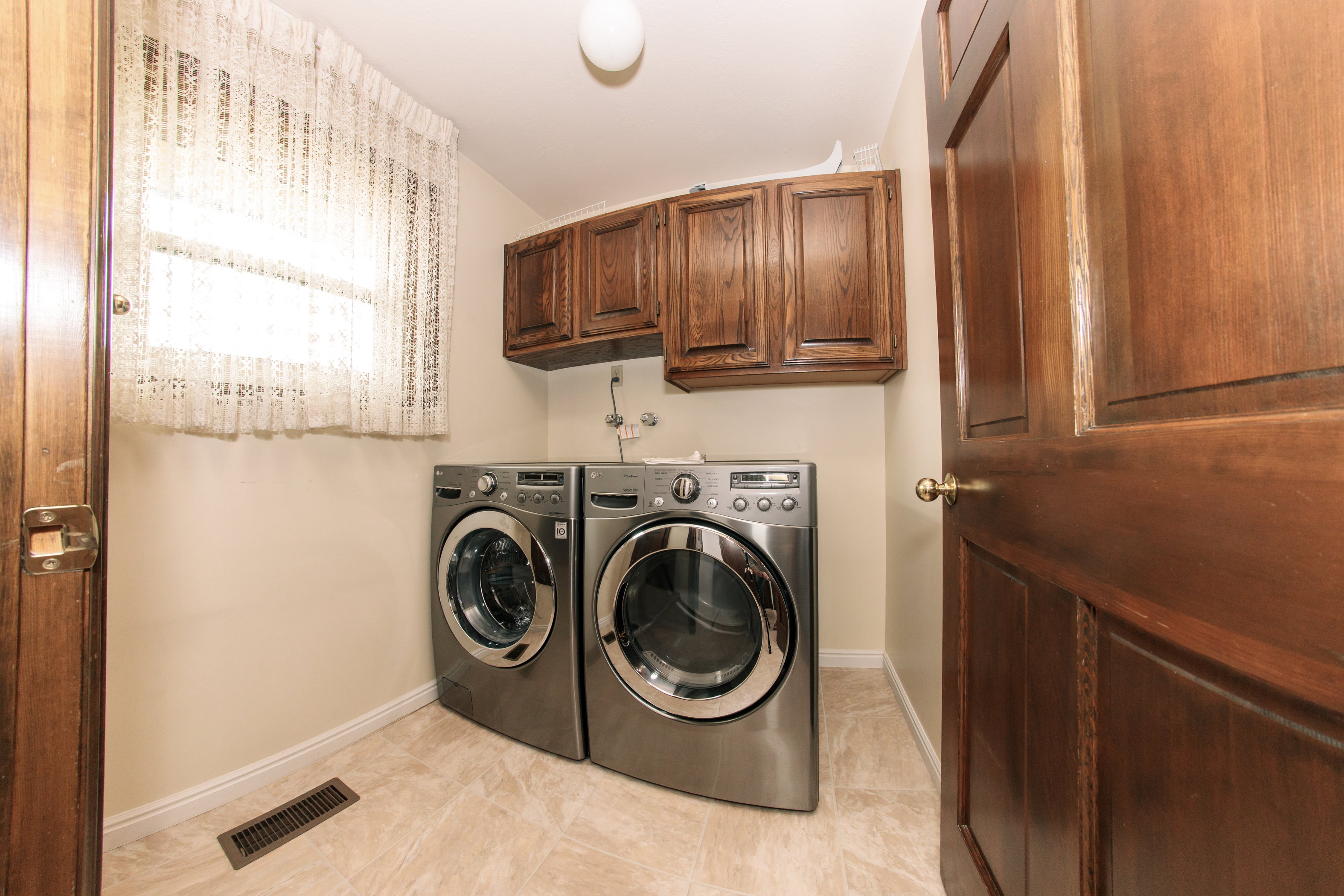 Utility space featuring a window, wood cabinetry, and tiled flooring