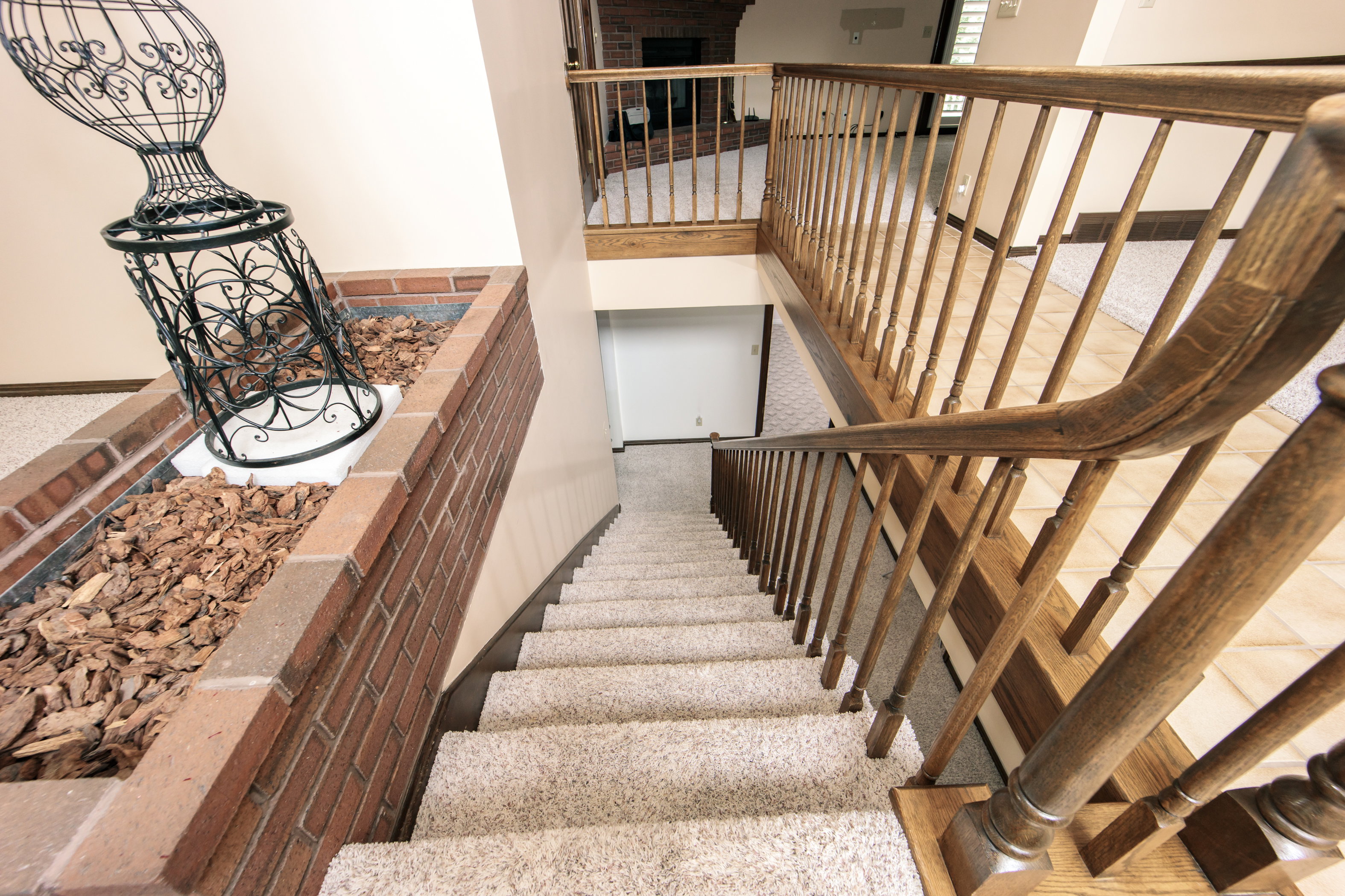 Carpeted staircase with wood-finish railings and balusters