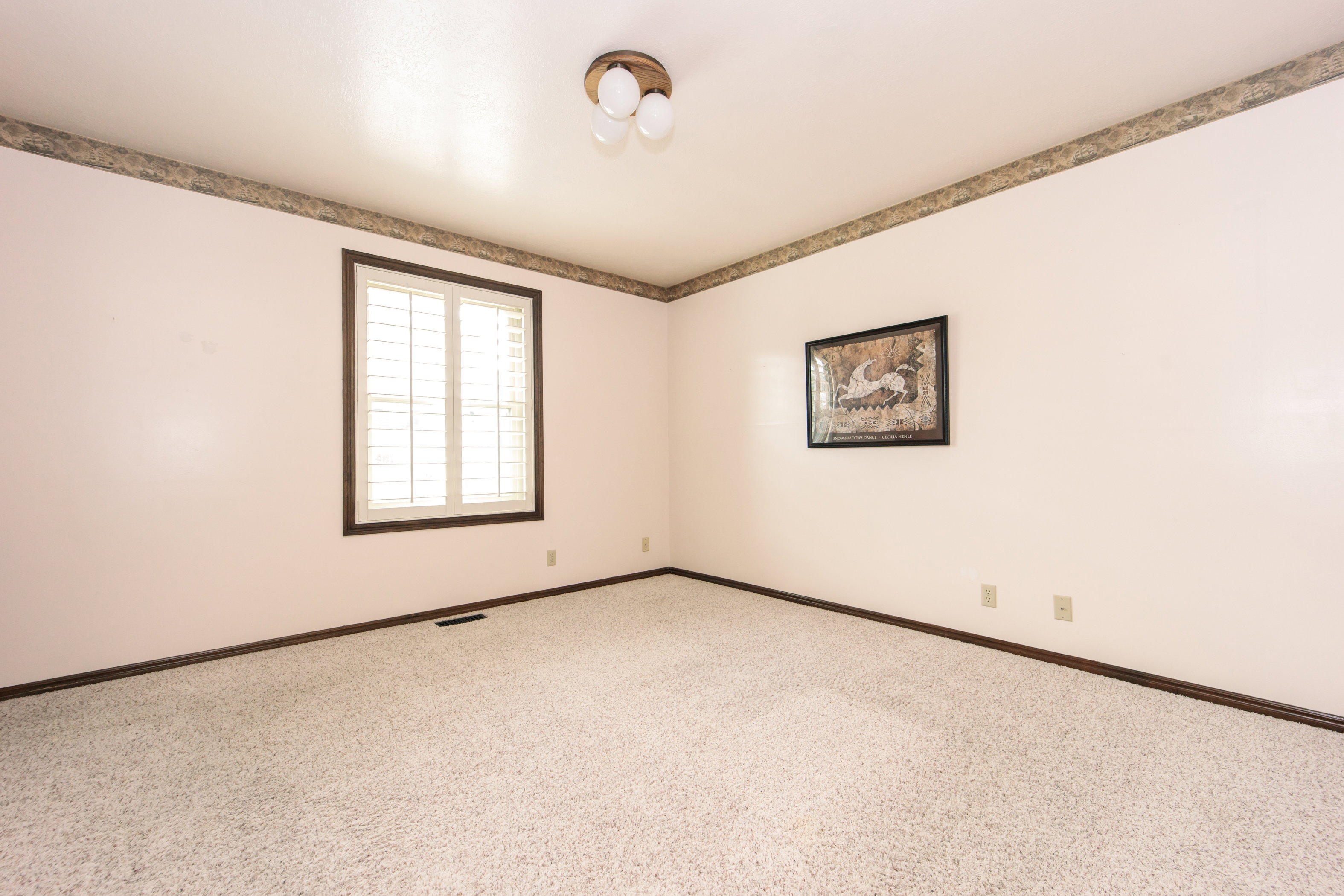 Room featuring carpet flooring and light-toned walls with a decorative border