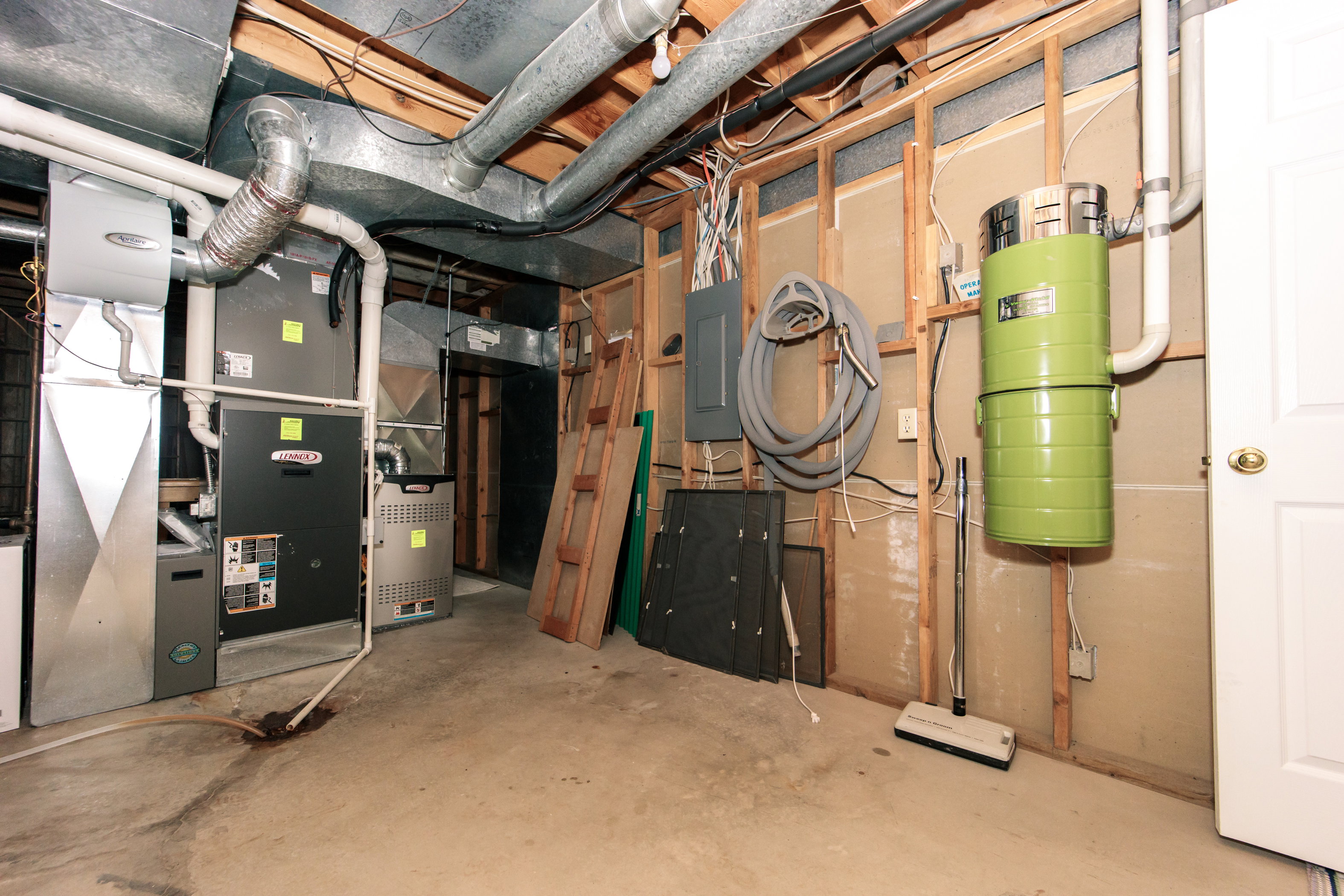 Mechanical room featuring two furnaces, an electrical panel, exposed ductwork, and a central vacuum system