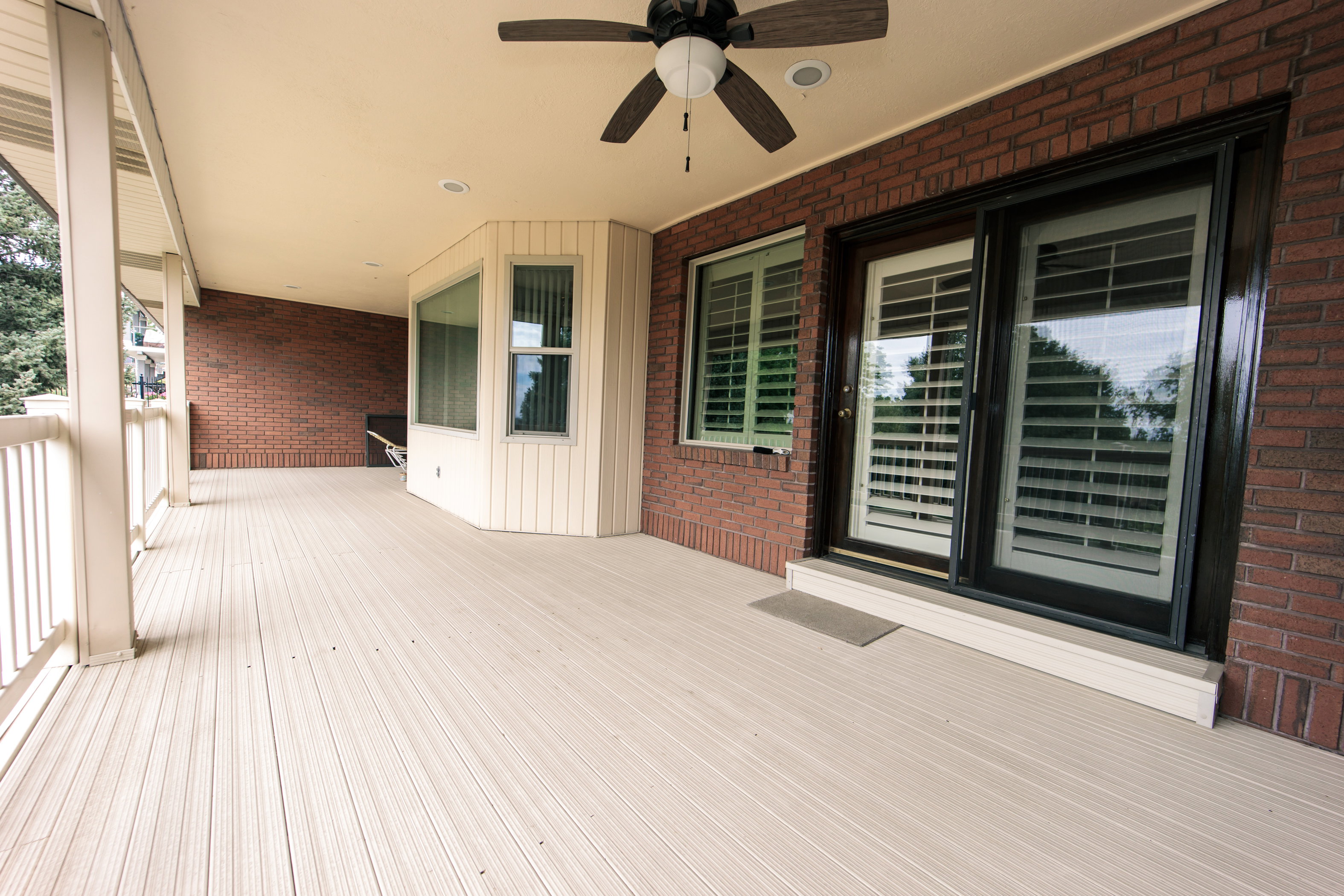 Expansive covered deck featuring composite decking, a ceiling fan, recessed lighting, and a bay window