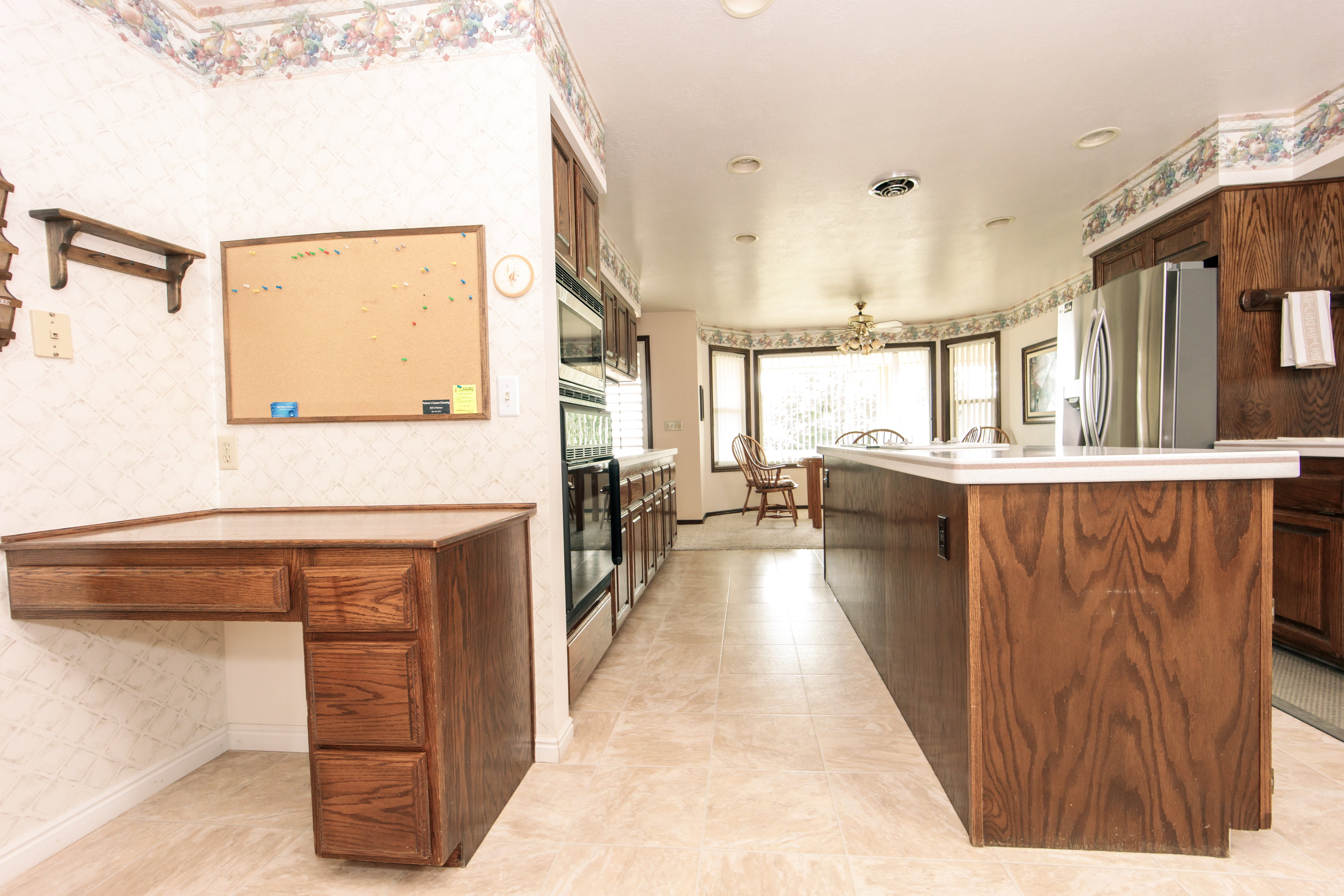 Spacious kitchen featuring an extended island with white countertops, integrated stainless steel appliances, wood-finish cabinetry, and recessed lighting