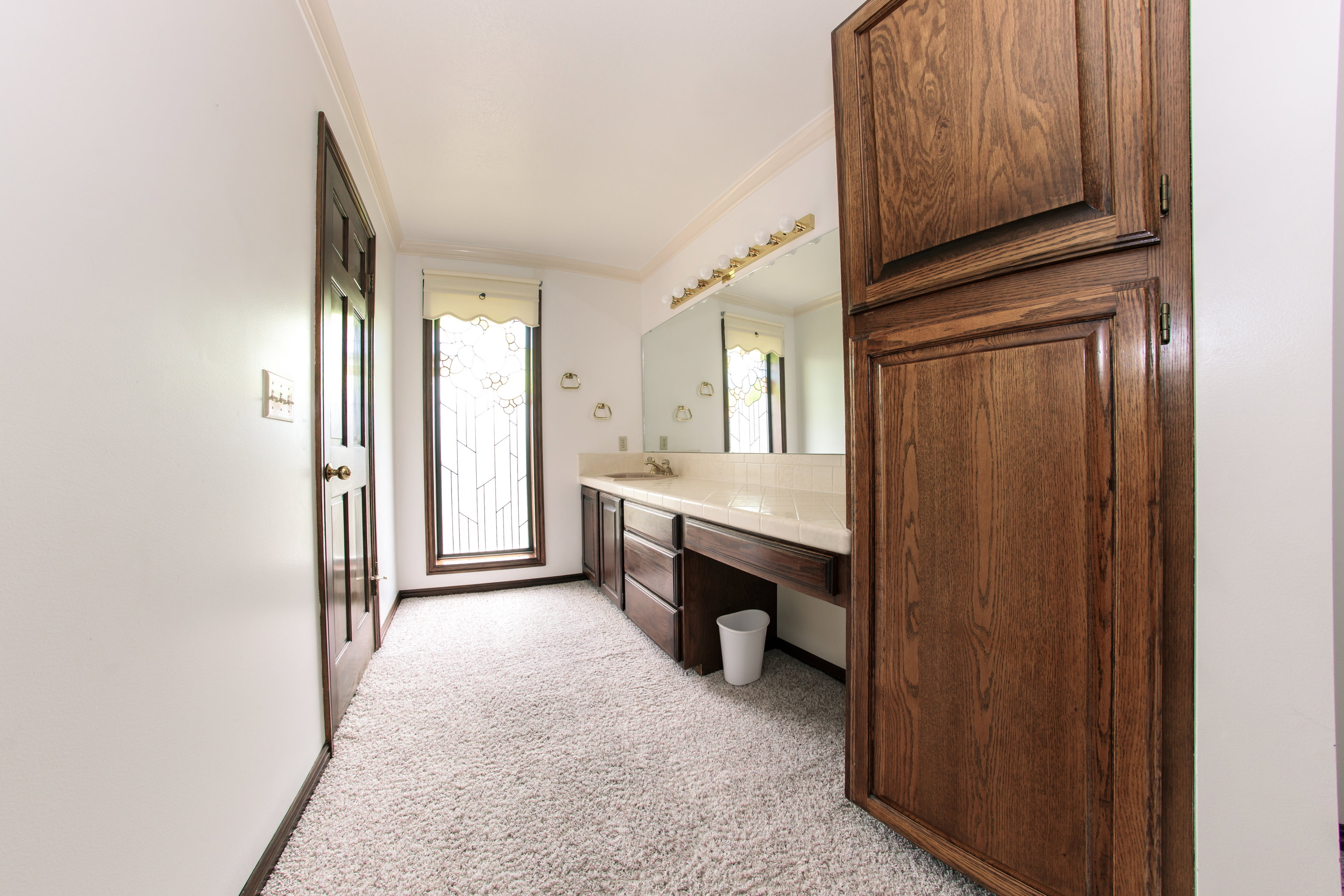 Spacious bathroom featuring a long vanity with dual sinks, extensive wood cabinetry, and a large mirror