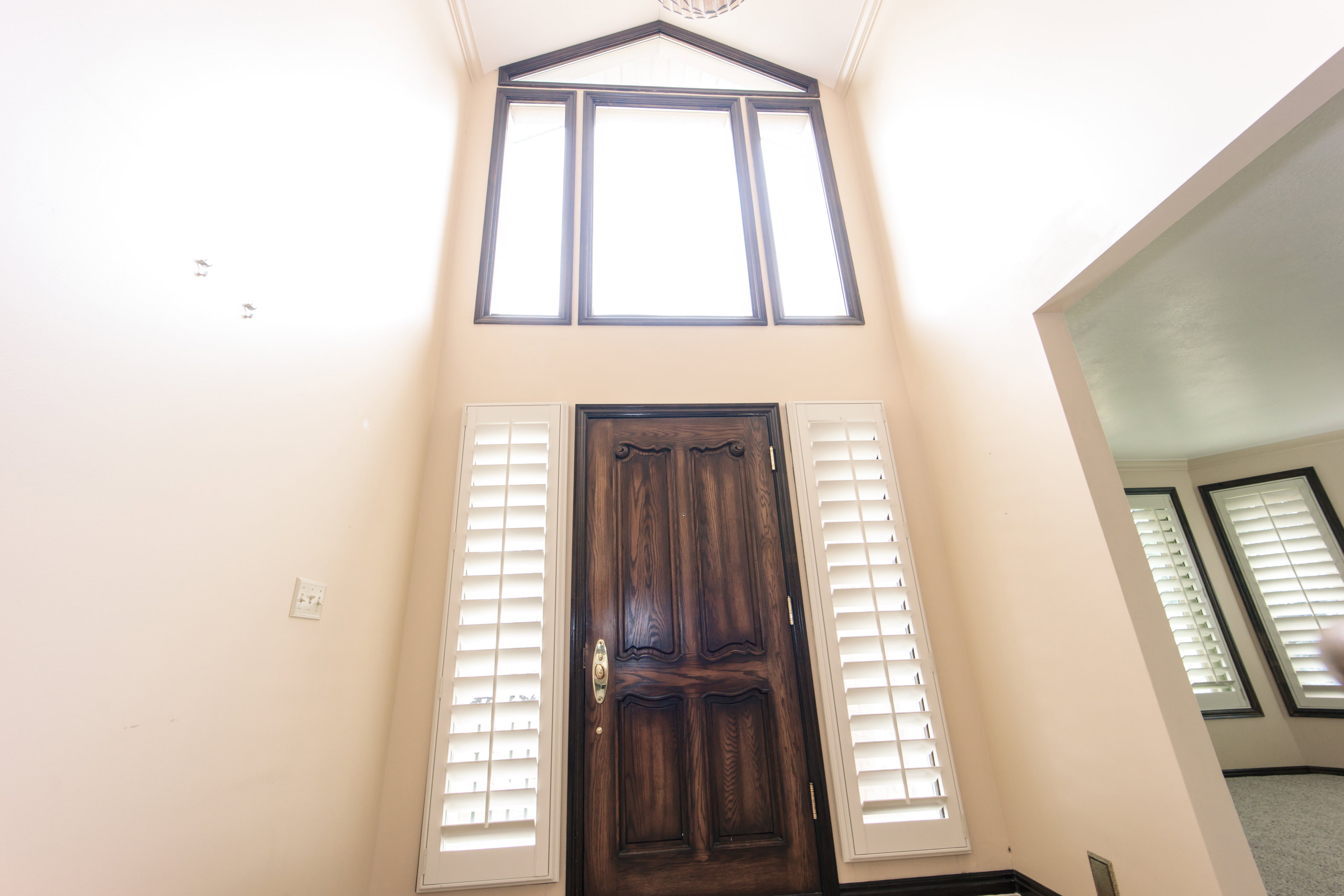 Grand entry featuring a dark wood paneled door with decorative carving and brass hardware