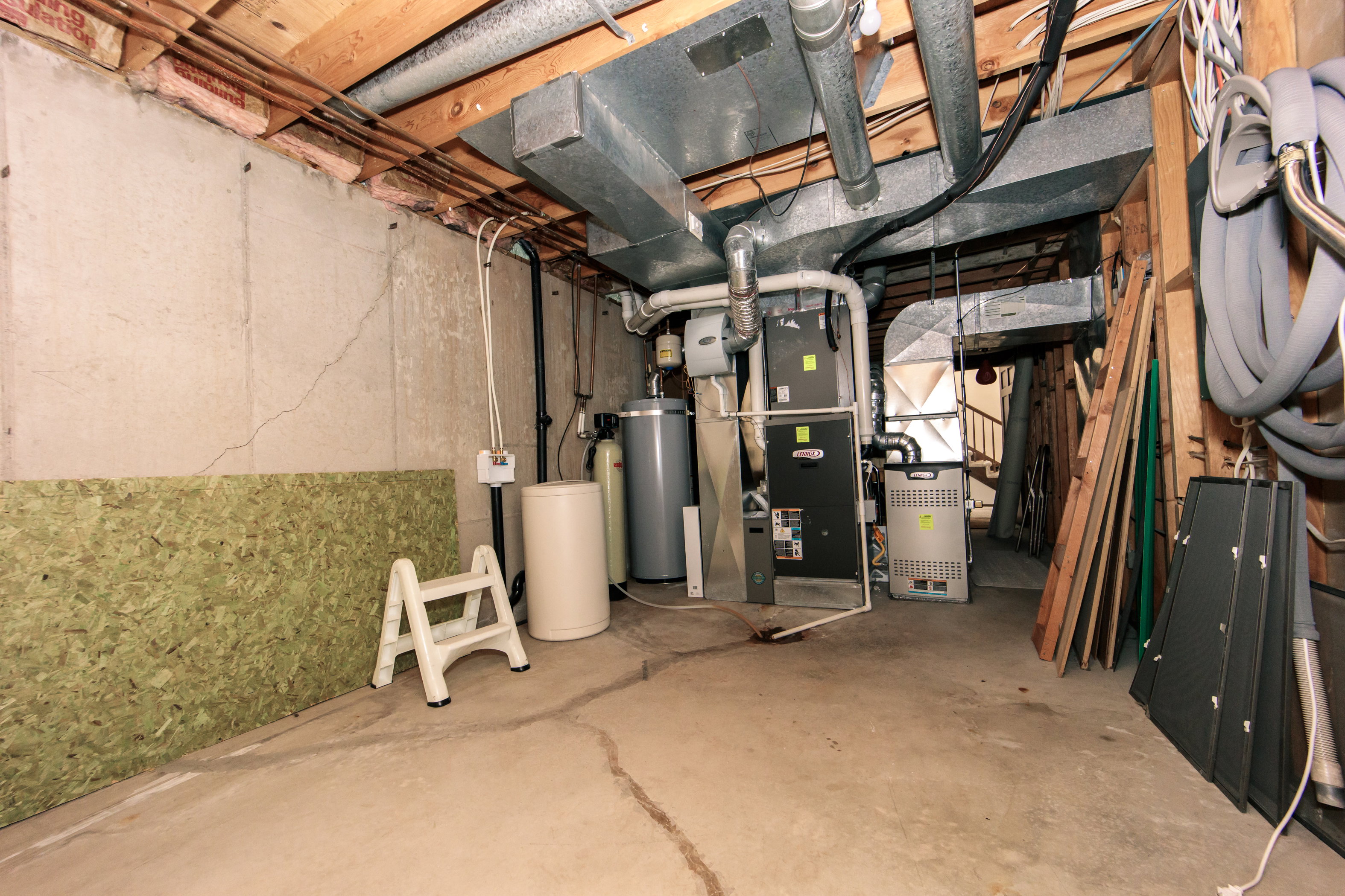 Utility area featuring a water heater, water softener, and furnace system with exposed ductwork