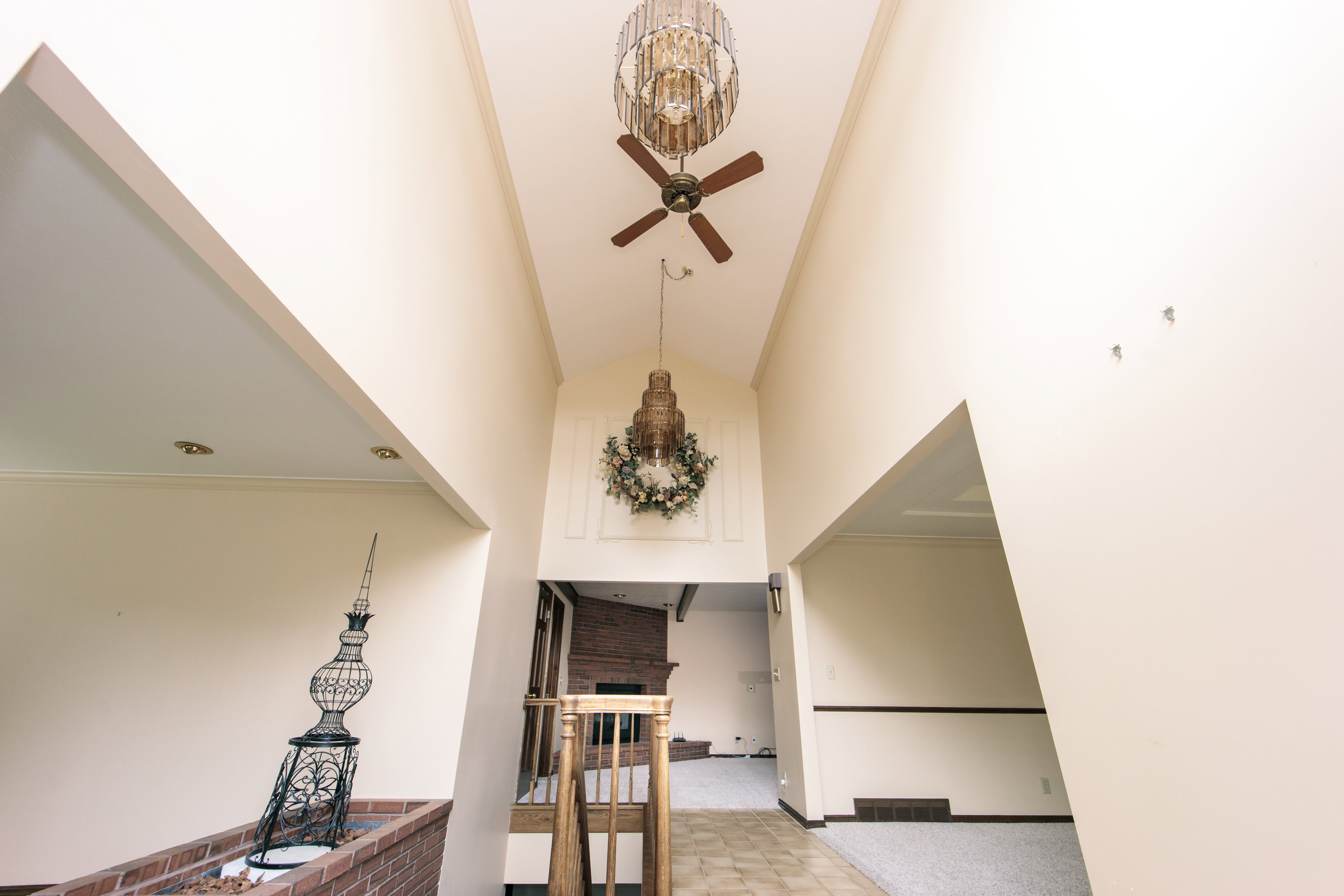 Vaulted entryway featuring a decorative light fixture, ceiling fan, and a paneled wall detail