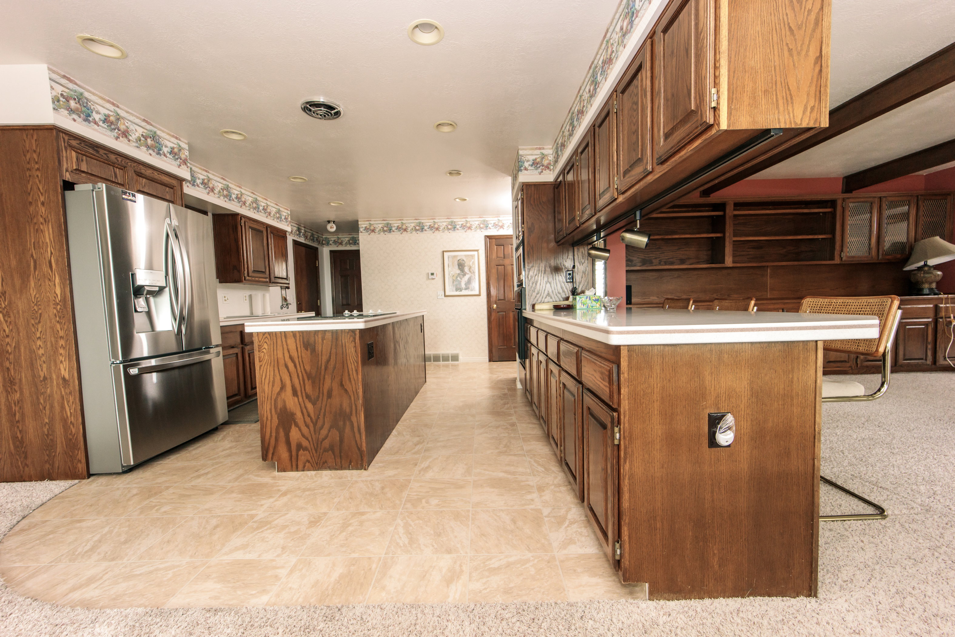 Expansive kitchen featuring a large central island, extensive wood cabinetry, and recessed lighting