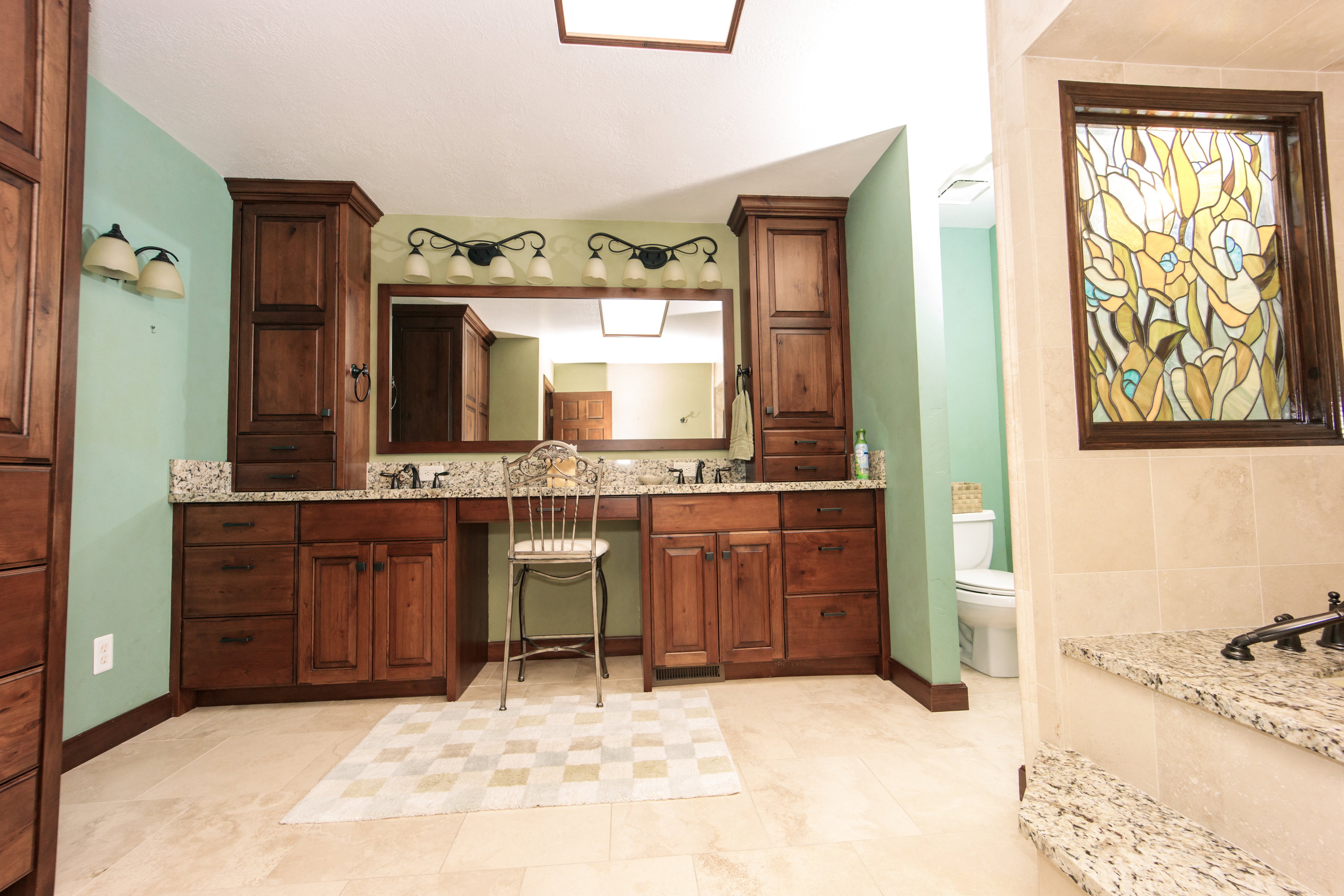 Expansive vanity area featuring dual sinks, rich wood cabinetry, and stone countertops