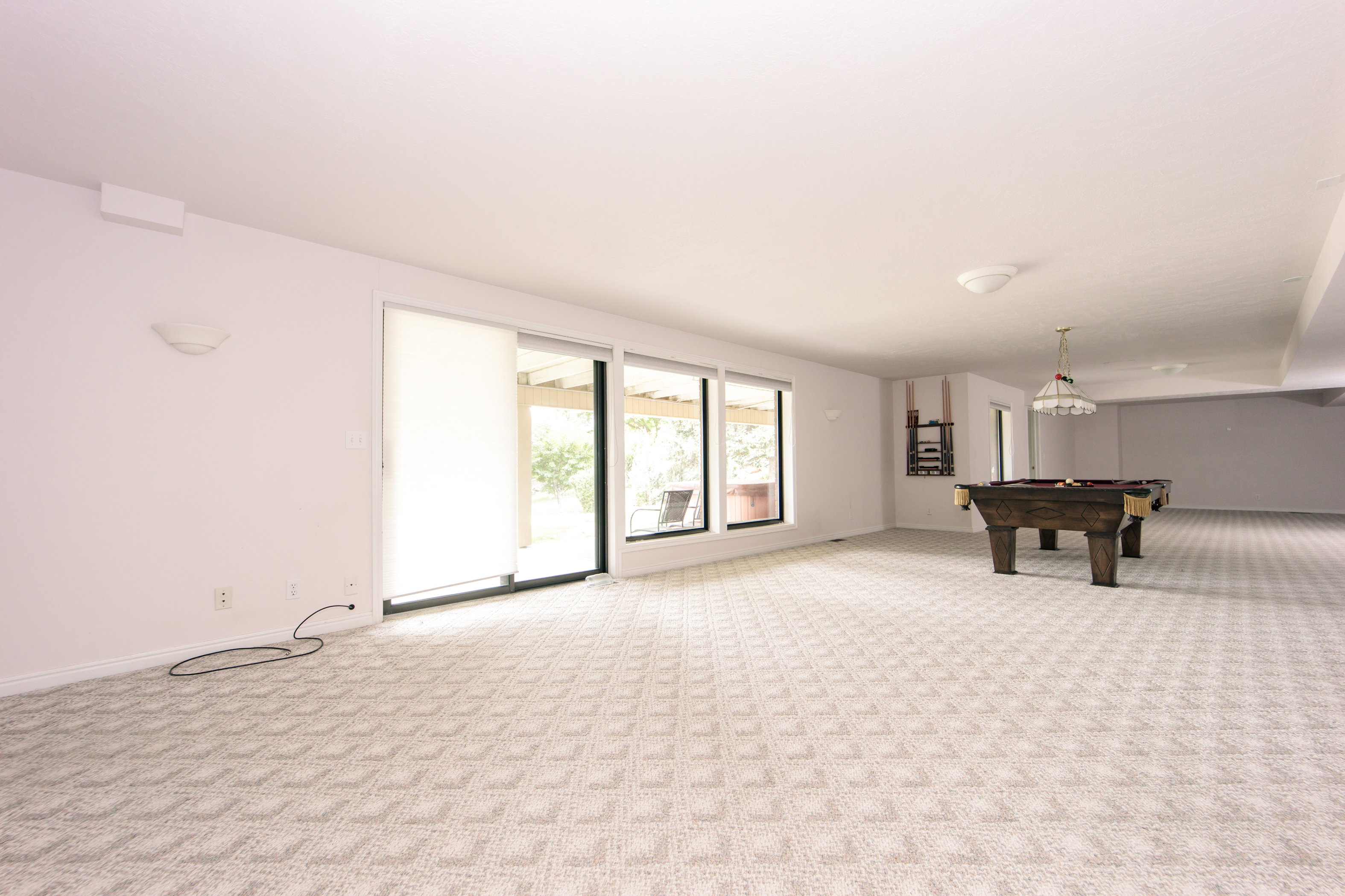 Spacious finished basement featuring patterned carpeting, multiple windows, and sliding glass doors