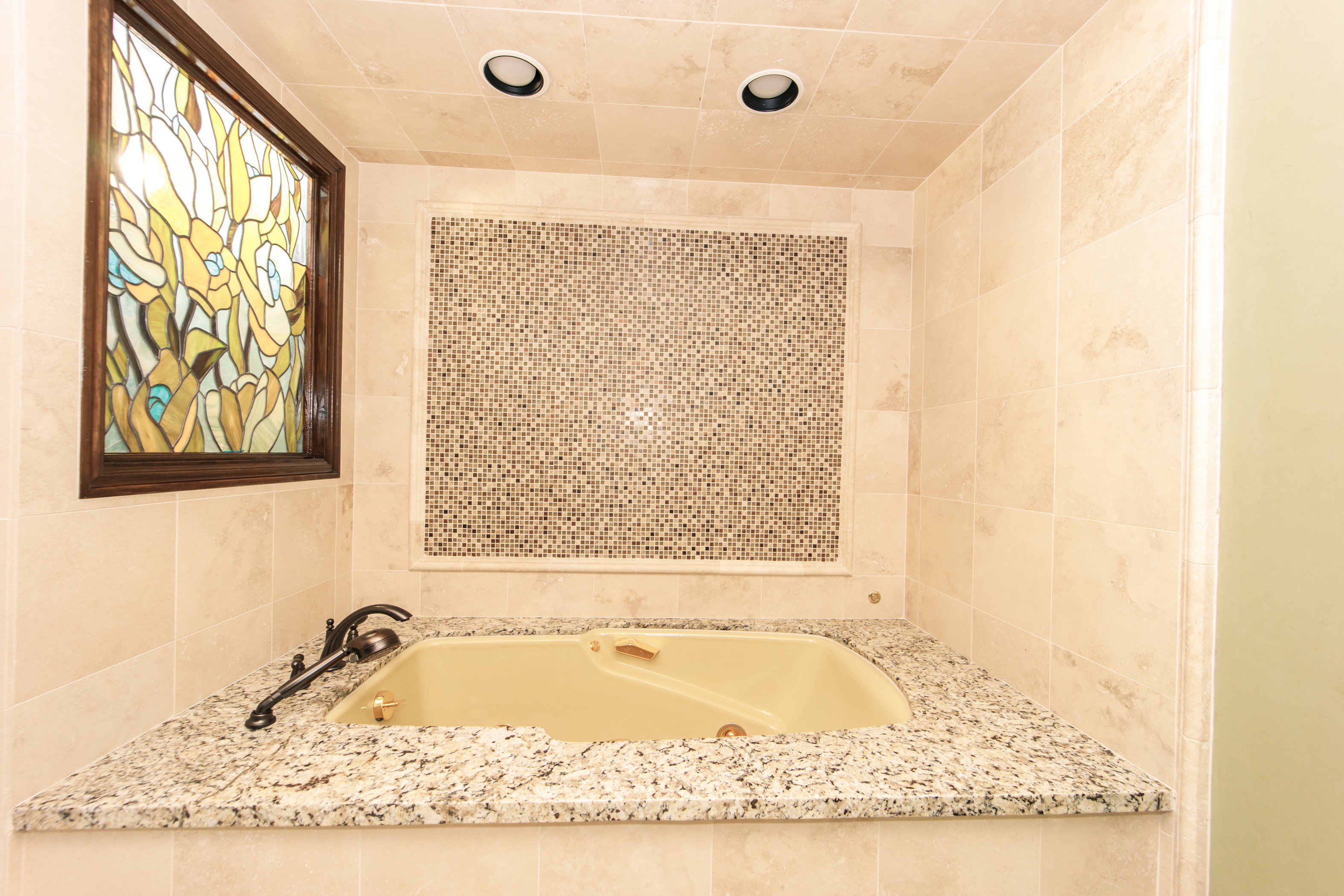 Corner soaking tub featuring a granite surround