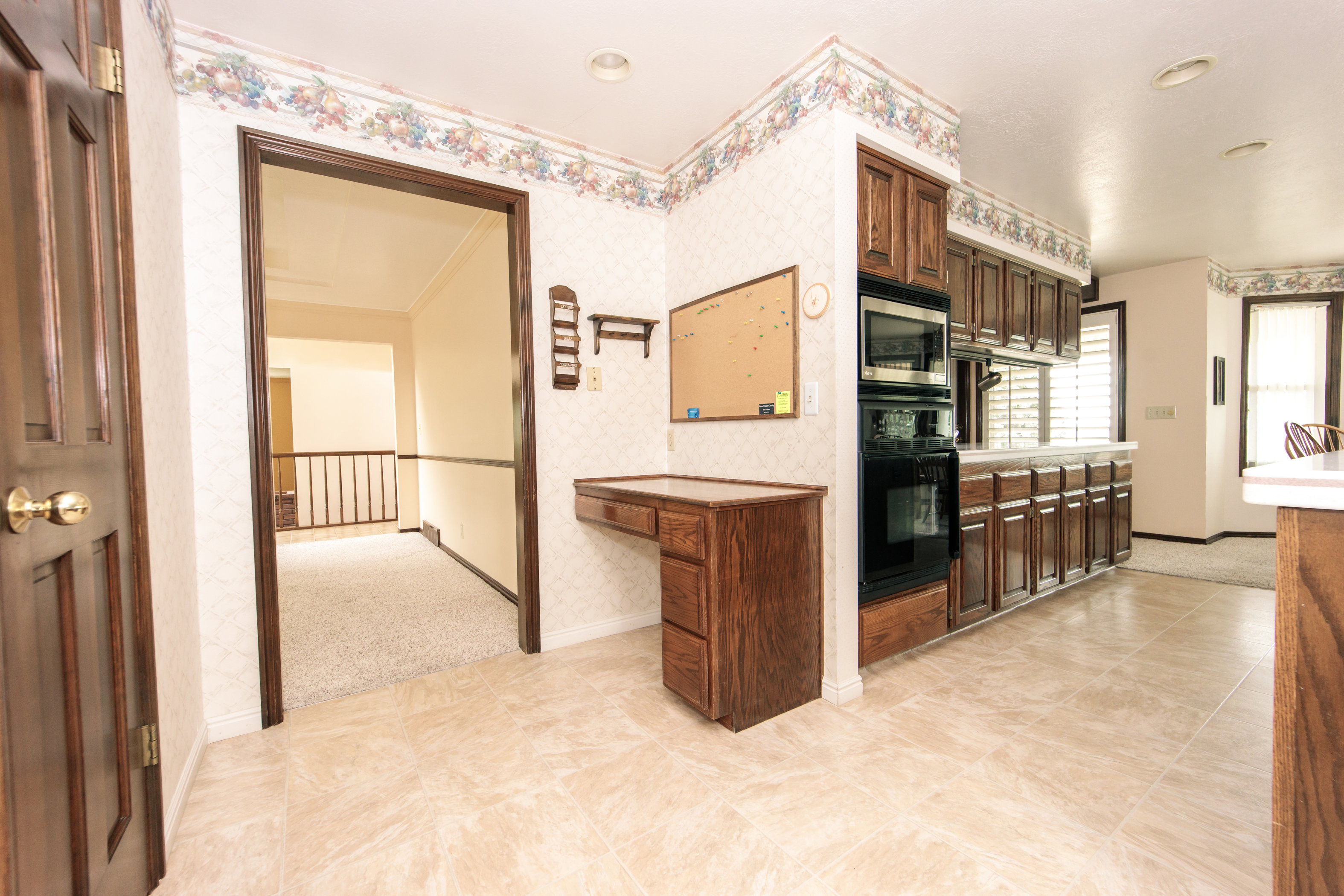 Kitchen area featuring wood cabinetry, built-in oven and microwave, and light-toned tile flooring