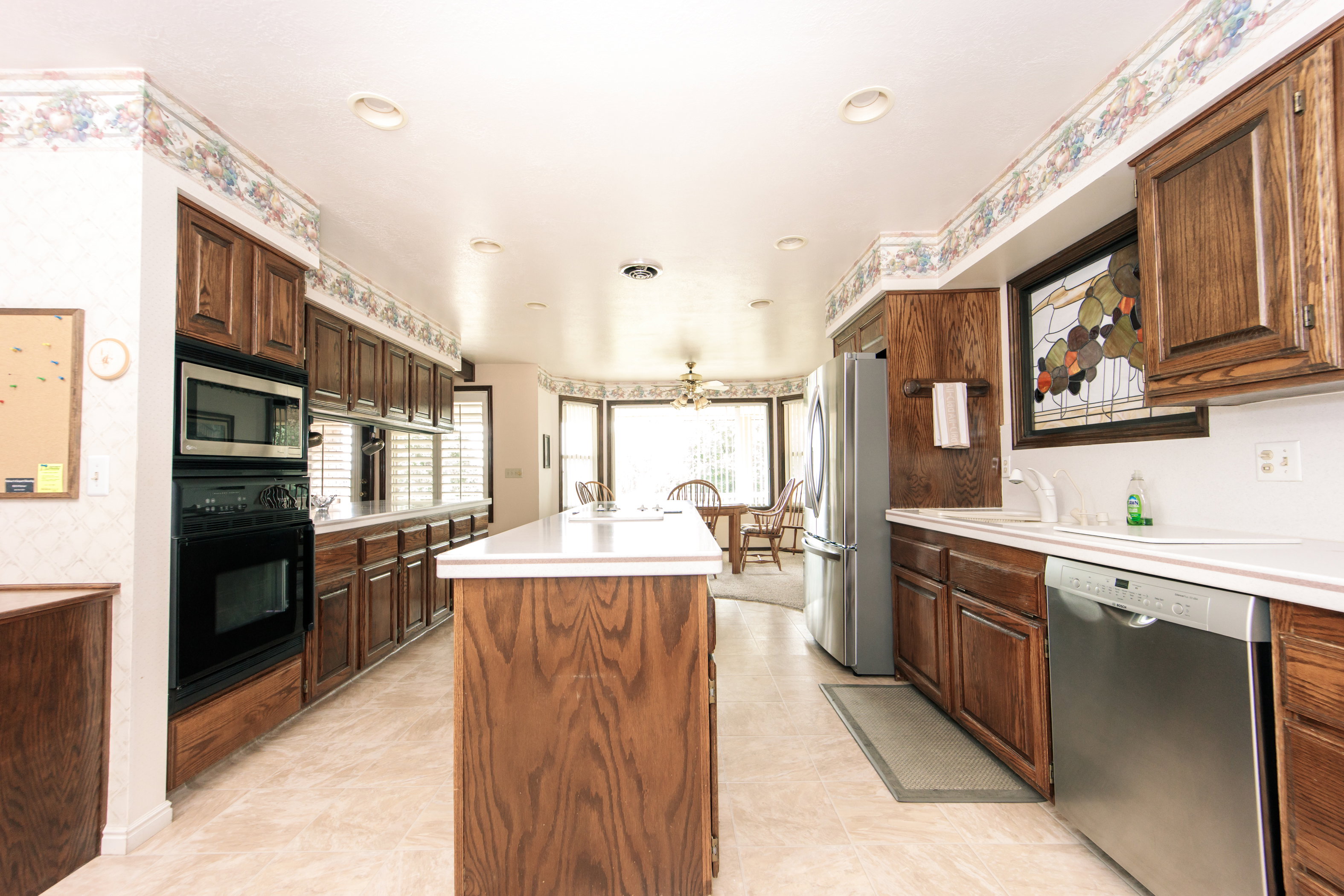 Kitchen featuring recessed lighting, extensive wood cabinetry, an integrated wall oven and microwave, a center island with countertop space, and a stainless steel dishwasher