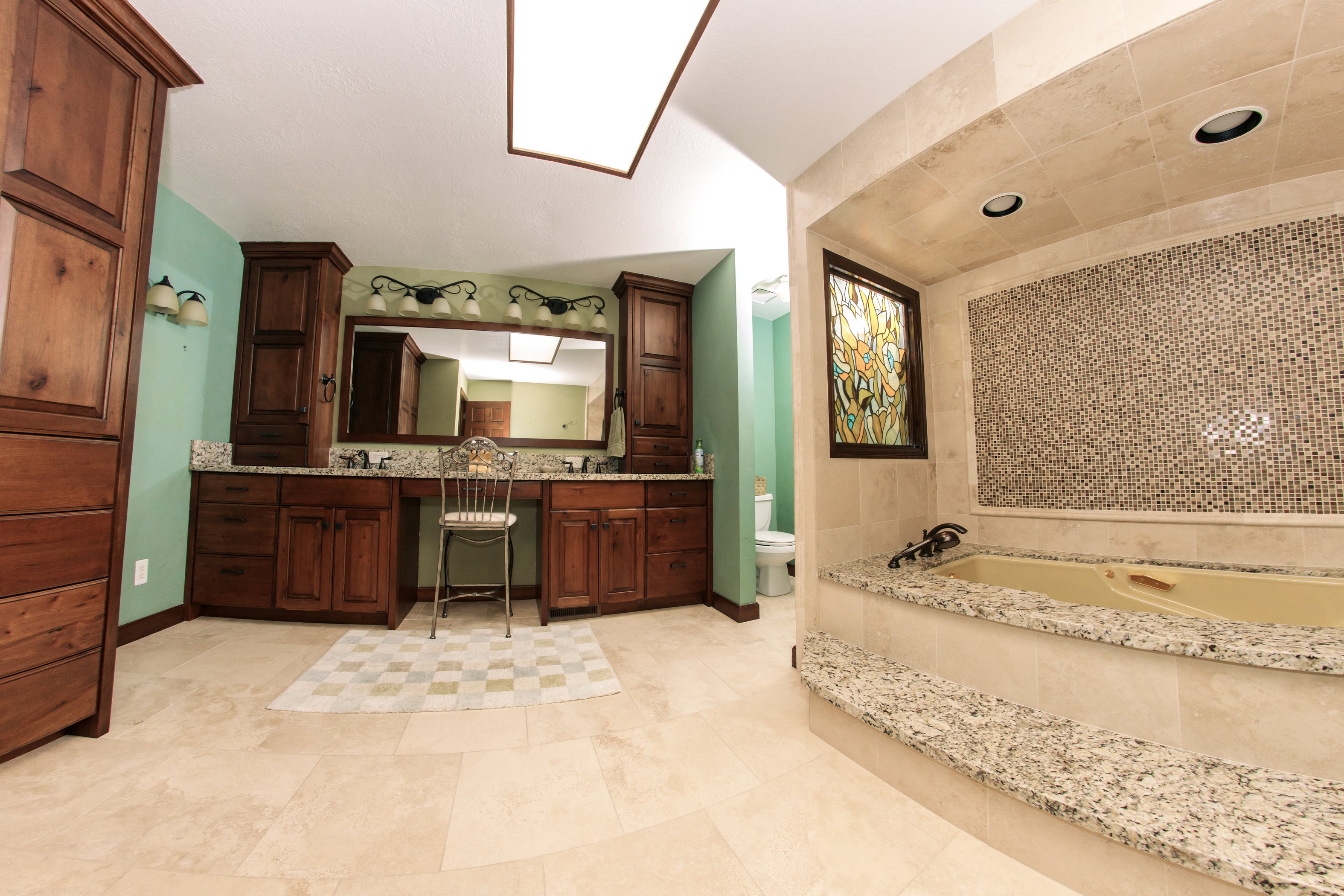 Spacious bathroom featuring a built-in soaking tub with granite surround and mosaic tile accent wall