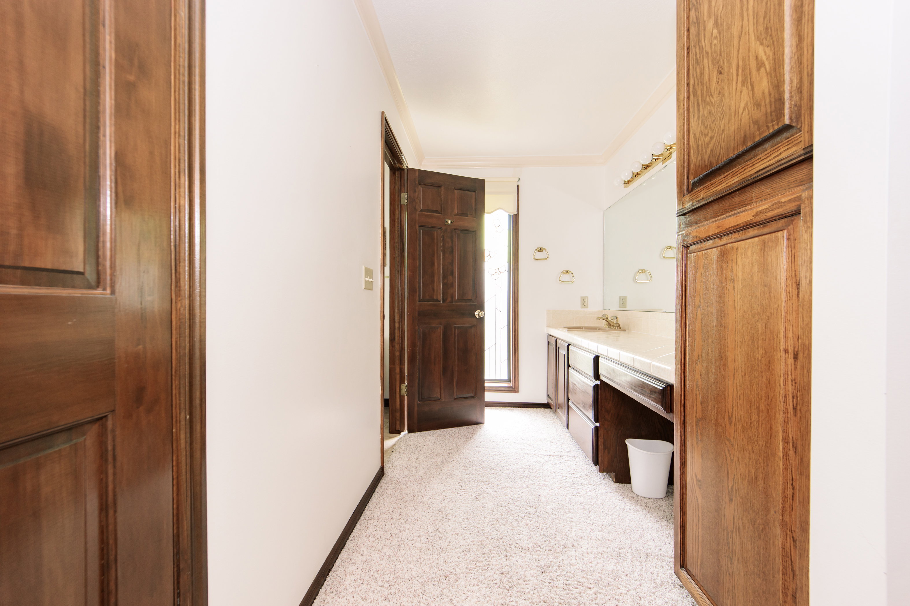 Bathroom featuring a long vanity with an integrated sink, a large mirror, and built-in wood cabinetry