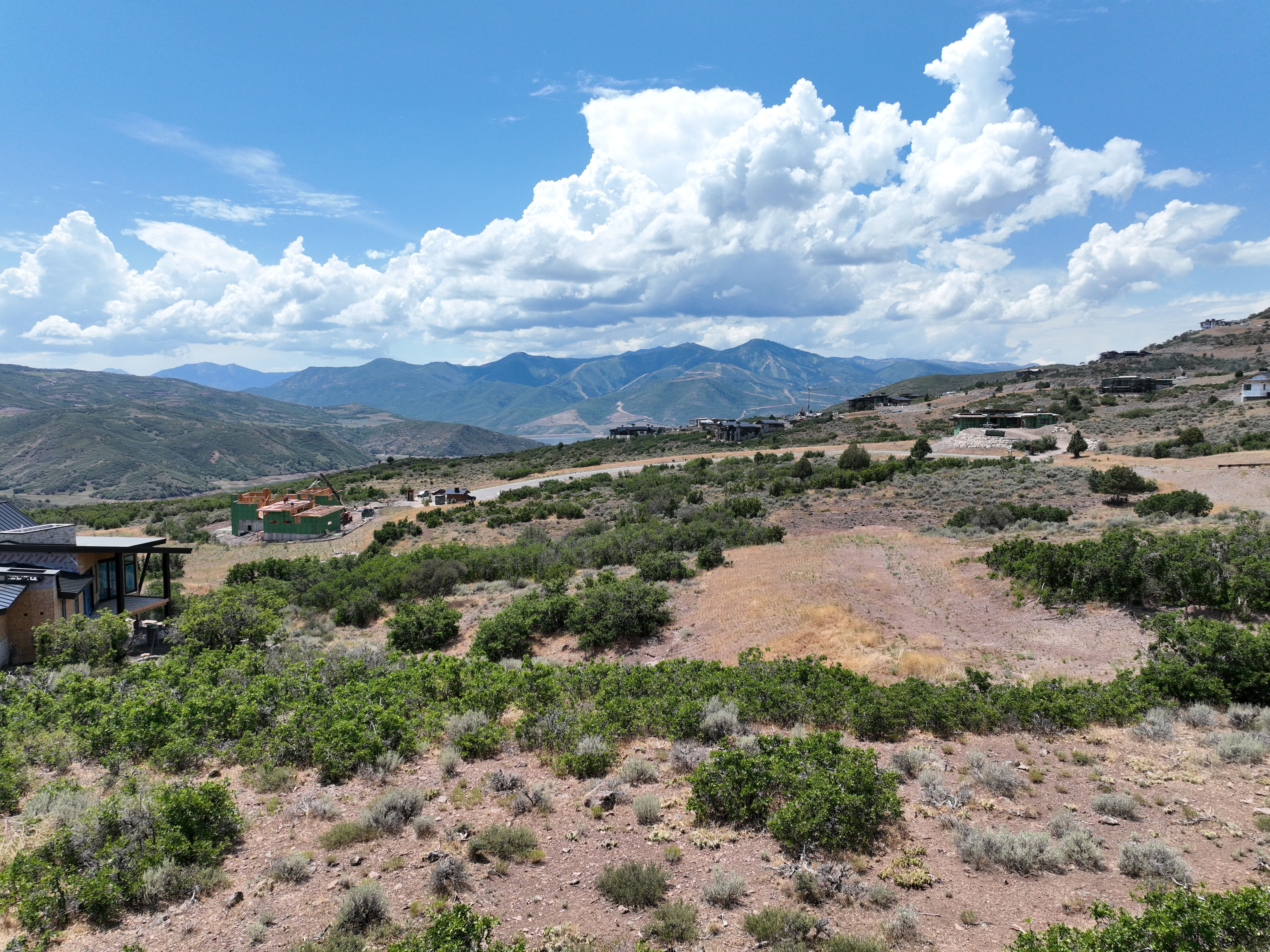 Expansive terrain featuring natural vegetation, distant mountain ranges, and a bright sky with cloud formations