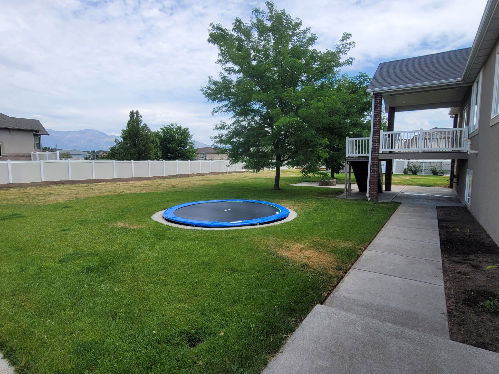 Expansive lawn area featuring mature trees and a perimeter privacy fence