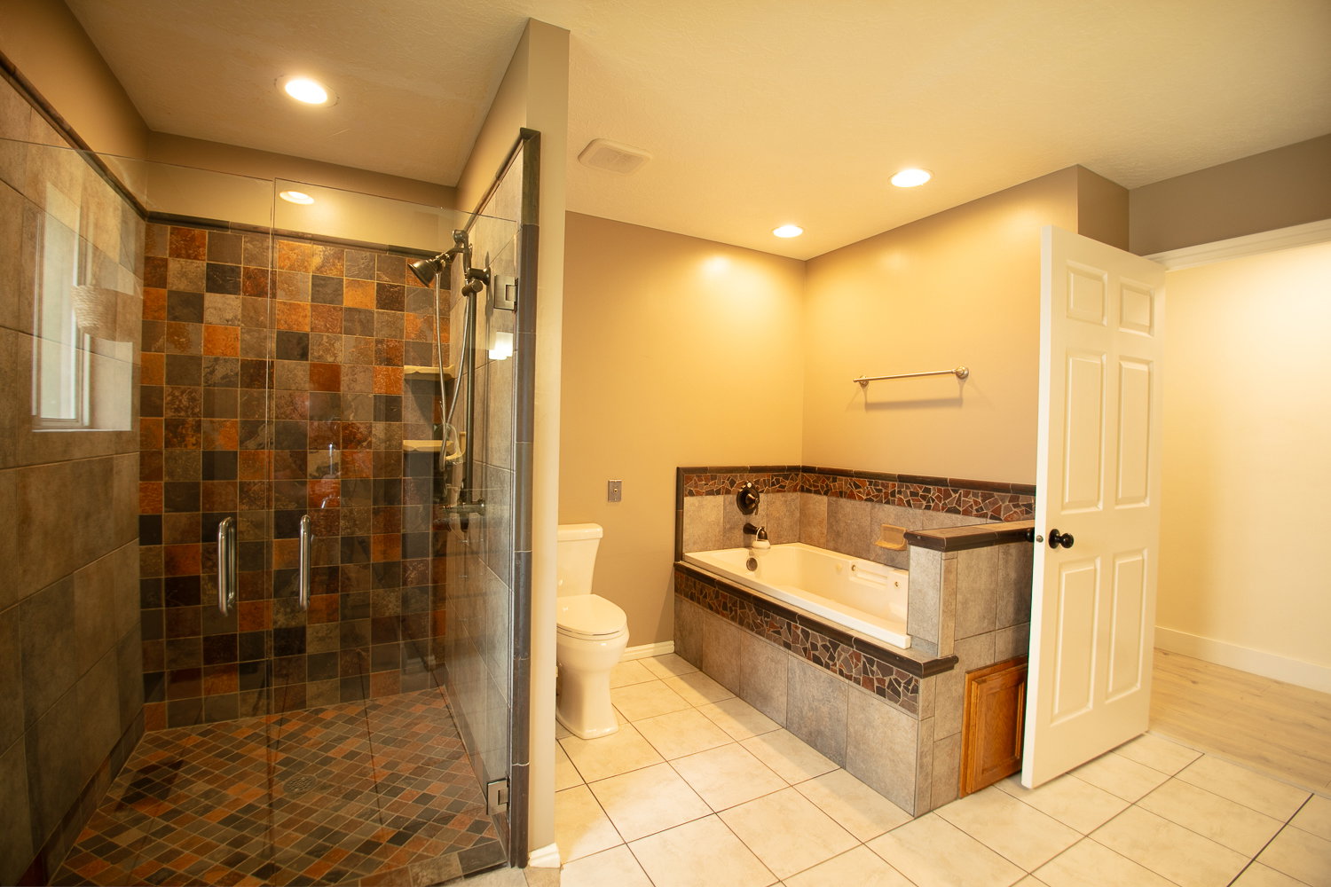 Spacious bathroom featuring a glass-enclosed shower with mosaic tile, a built-in jetted tub surrounded by tile, and recessed lighting