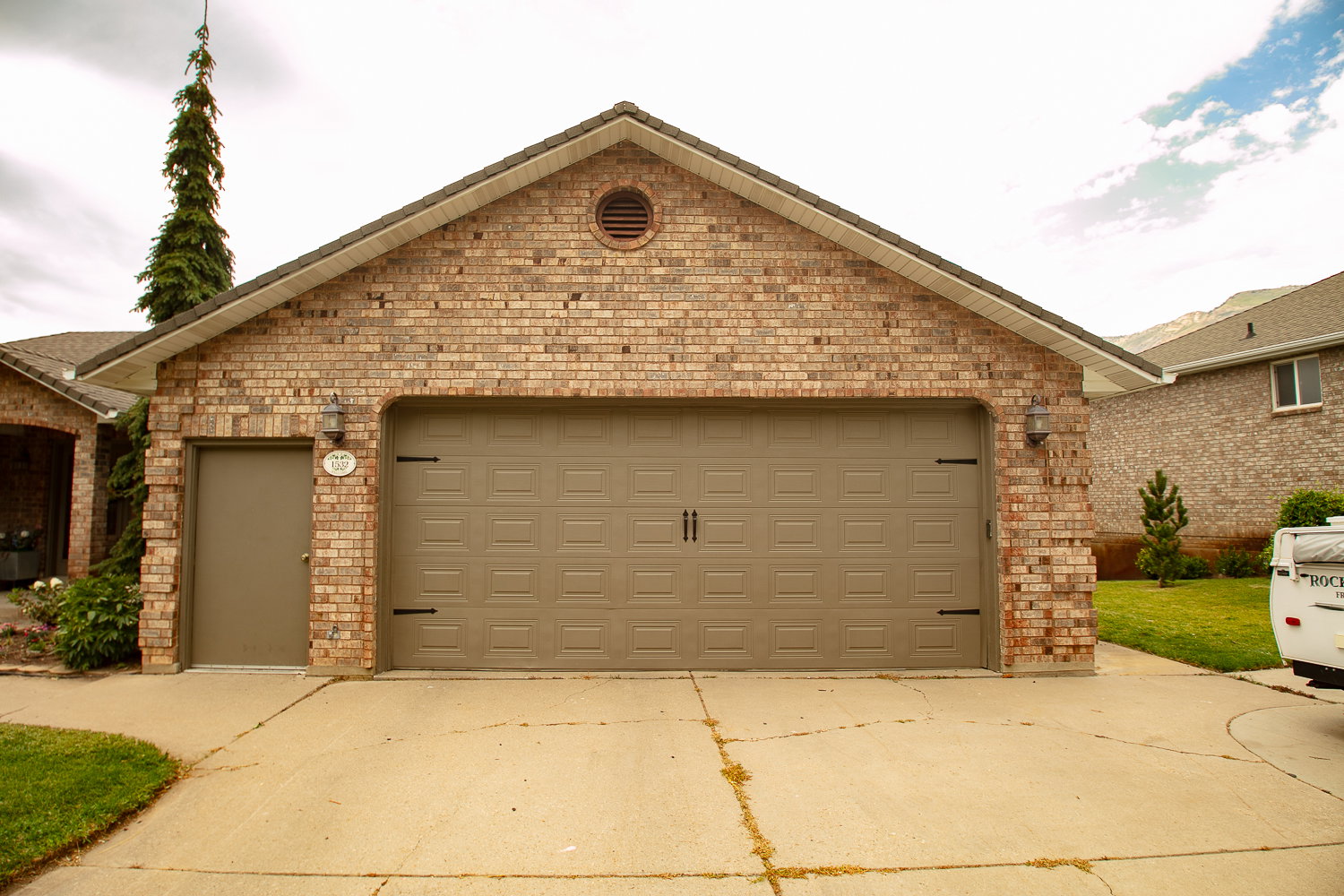 Brick exterior featuring a two-car garage with an additional side entry door