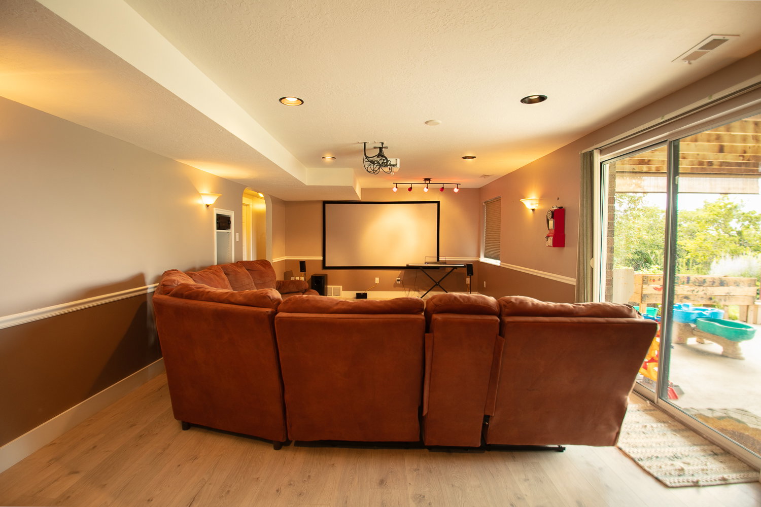 Entertainment area featuring a projector screen, ceiling-mounted projector, and track lighting