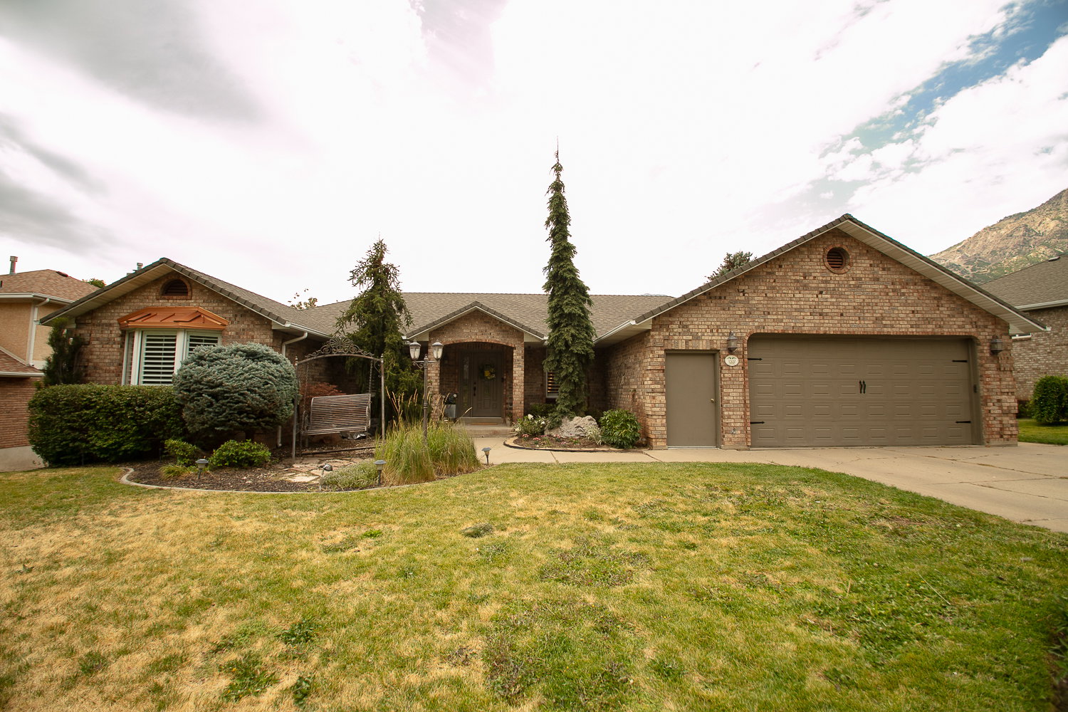 Brick exterior featuring an attached two-car garage with a brown door