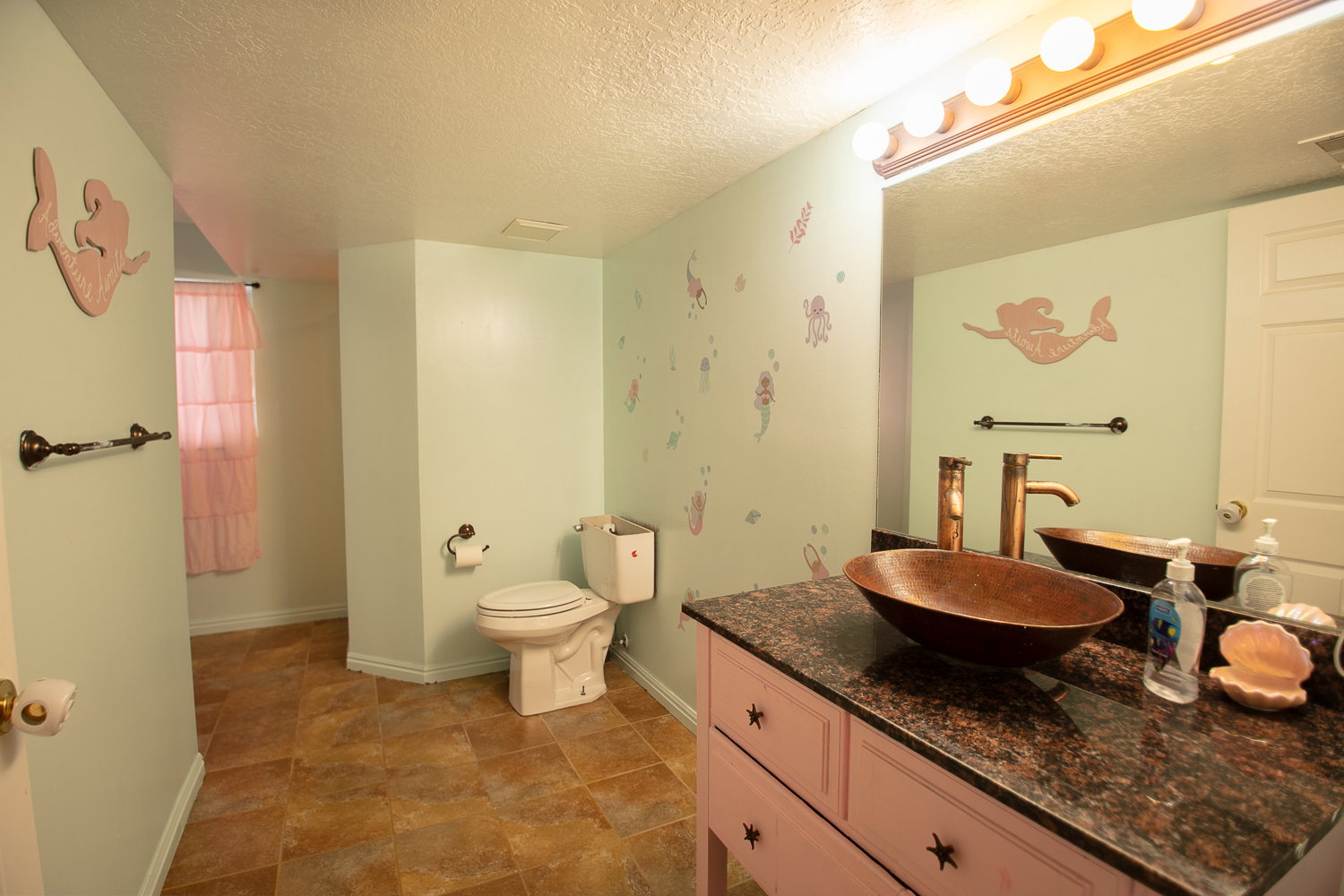 Bathroom featuring a vessel sink, dark countertop, and tiled flooring