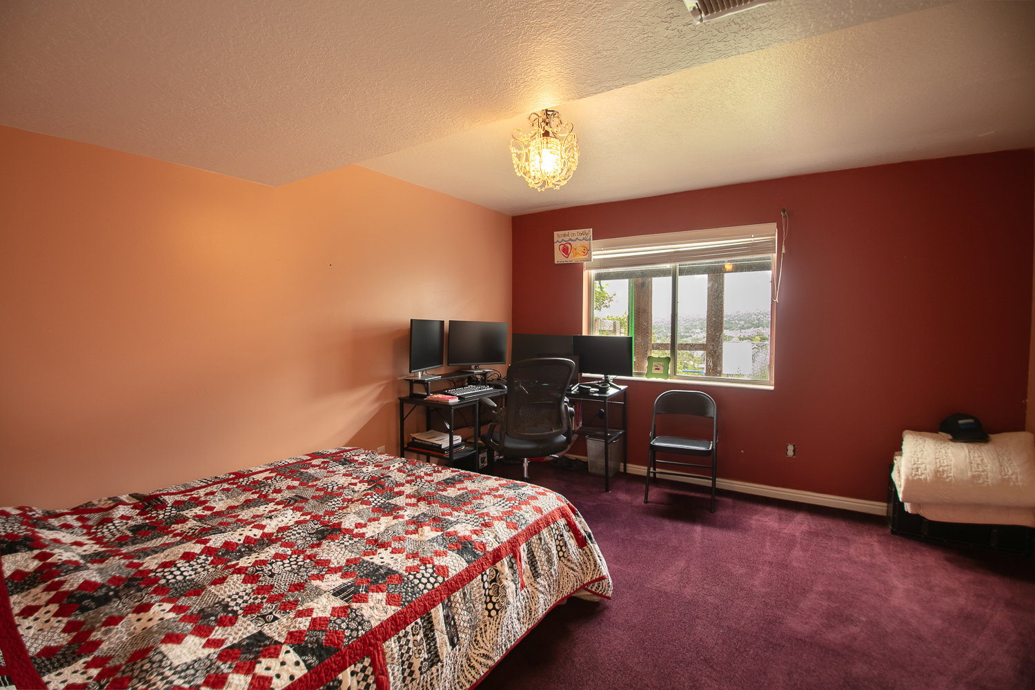 Bedroom featuring a large window, deep-pile carpet, and a decorative ceiling light fixture.  This bedroom just needs an armoire or a closet added to be a 6th bedroom.