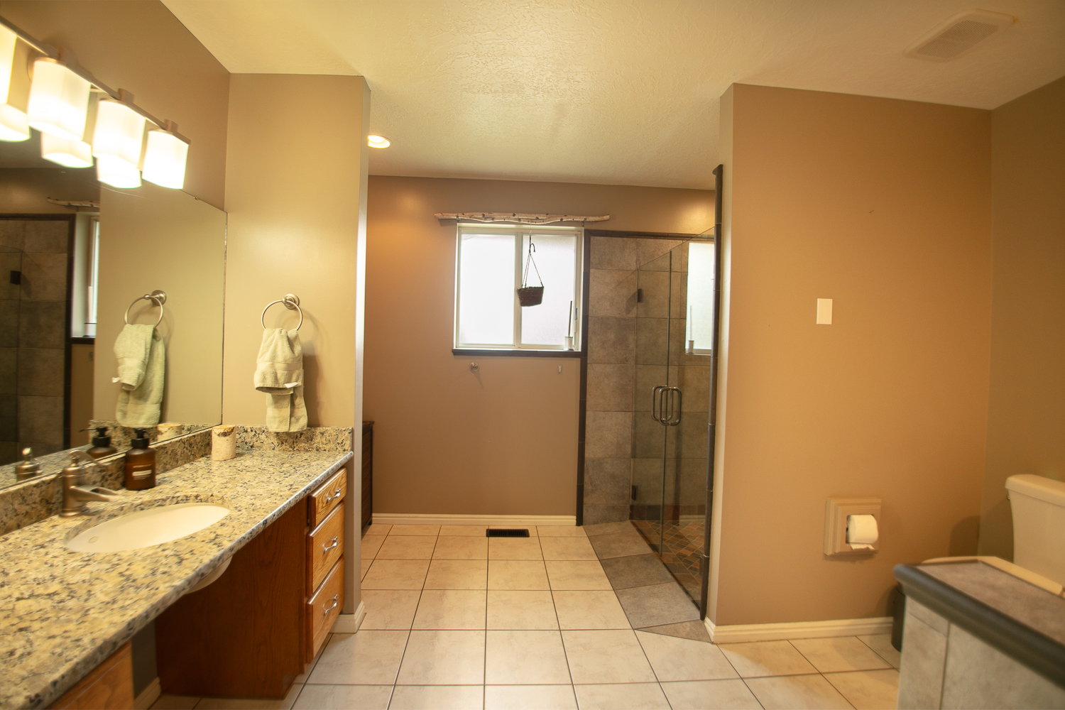 Bathroom featuring a granite-topped vanity with an undermount sink, a large wall mirror, and a multi-light fixture
