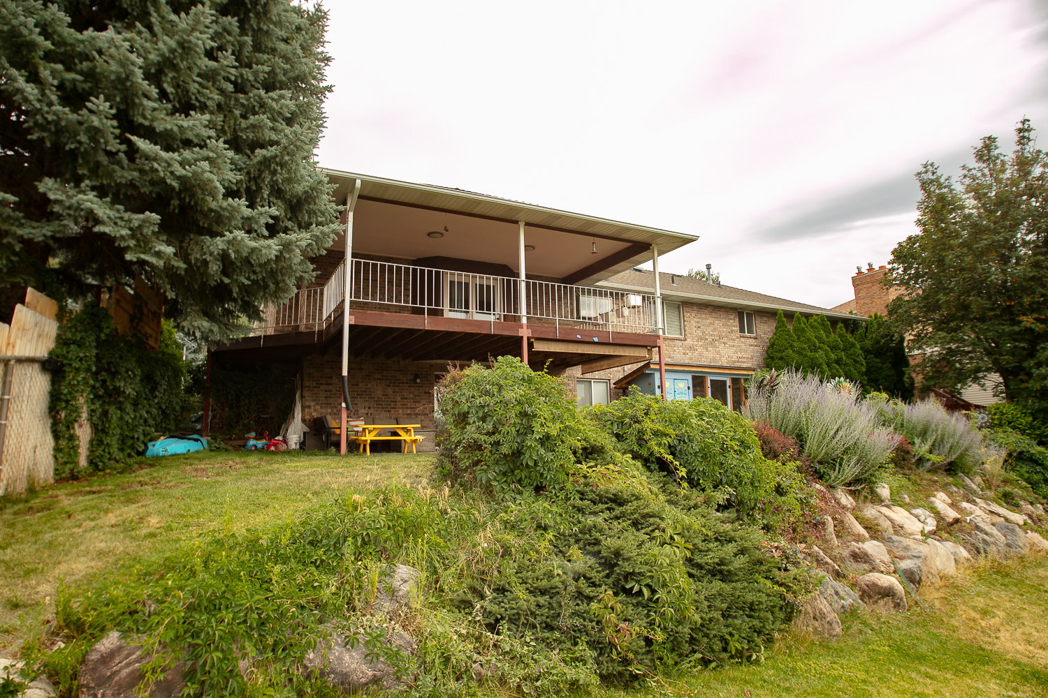 Expansive backyard featuring a multi-level deck with a covered upper portion, white railing, and dual glass doors