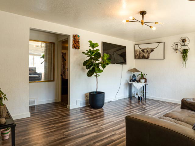 Spacious room featuring wood-finish flooring, white walls, and a contemporary ceiling light fixture
