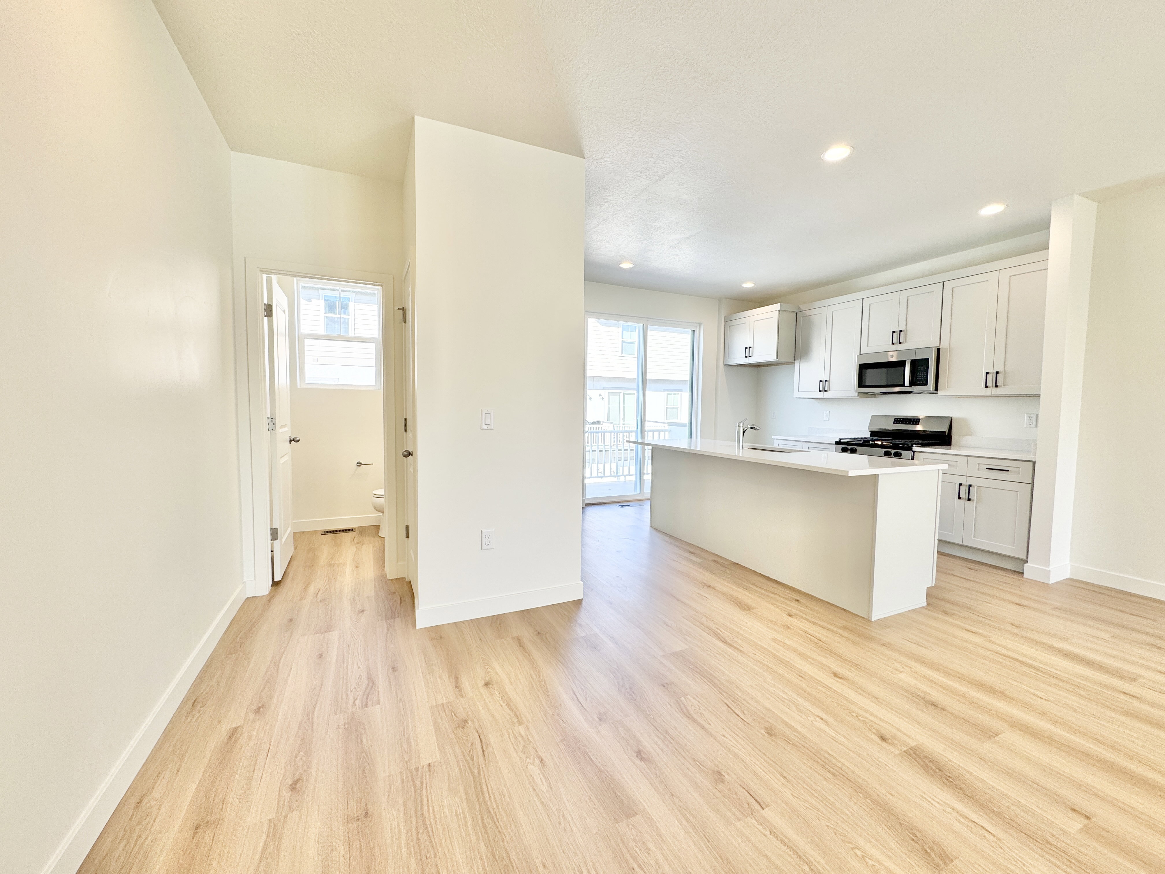 Open-concept kitchen featuring an island, white cabinetry, stainless steel appliances, and a gas range