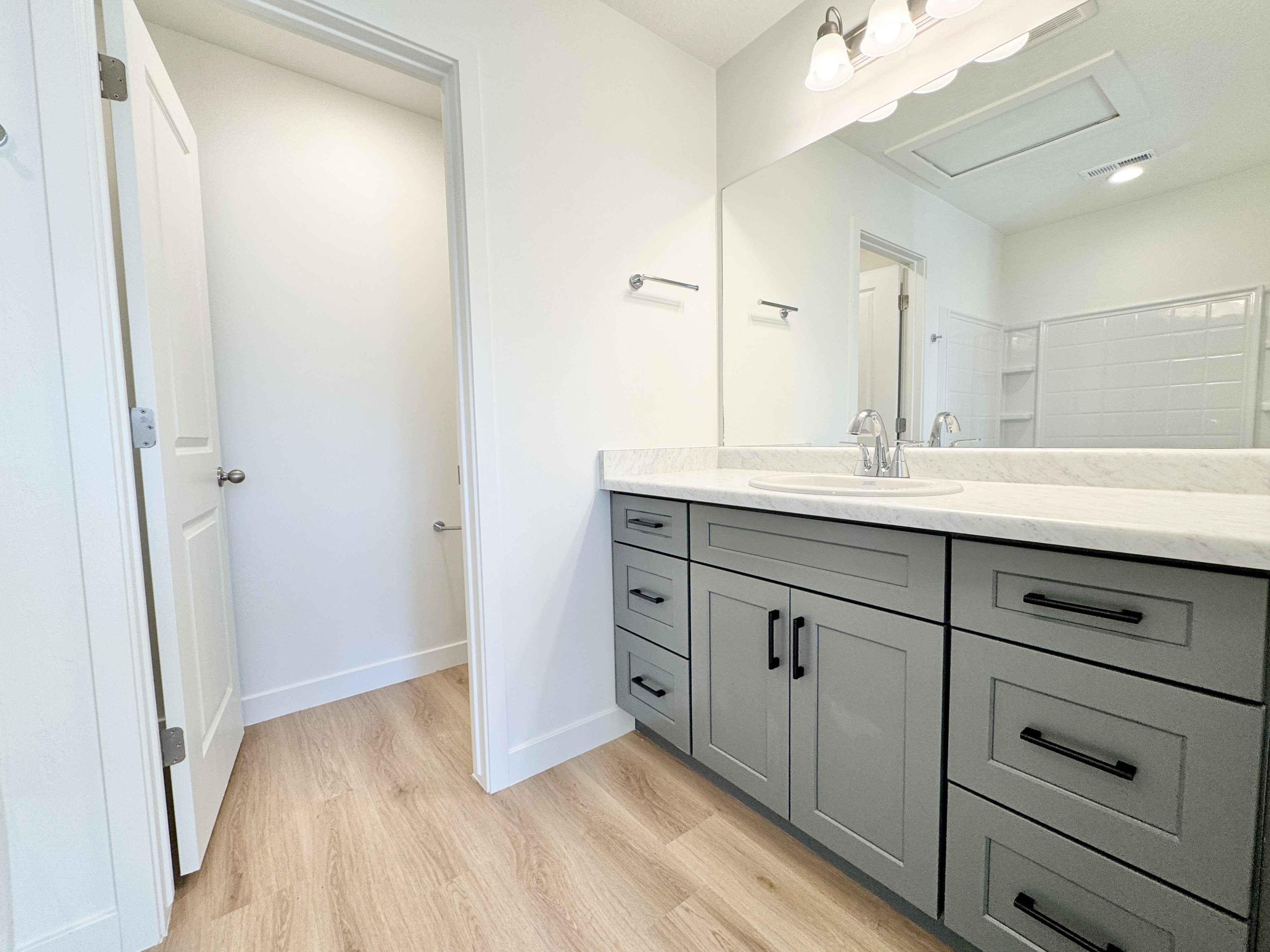 Vanity featuring a single undermount sink, a chrome faucet, and a large mirror