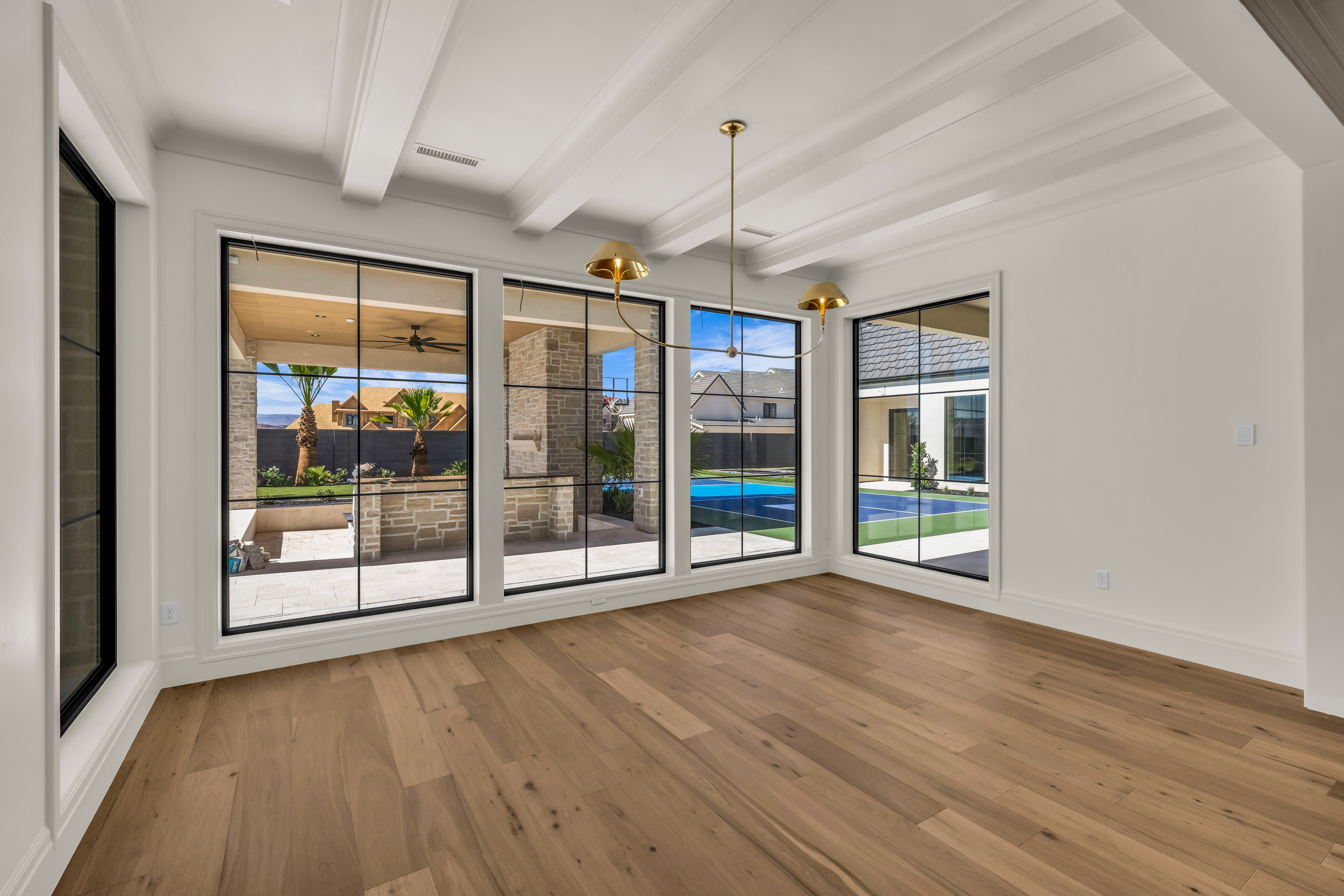 Interior space featuring wide plank wood-finish flooring, a coffered ceiling, and large windows with black framing