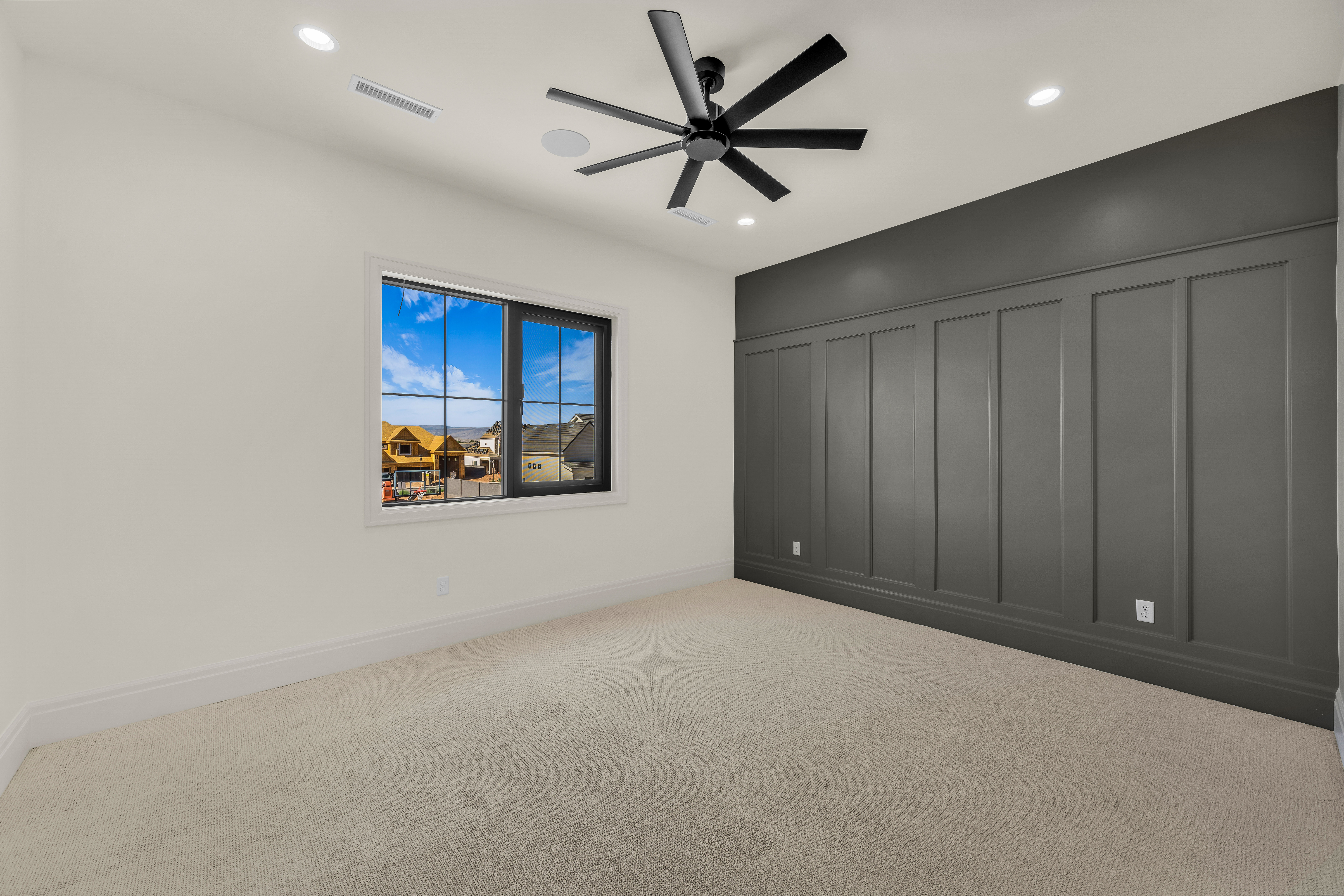 Neutral carpeted room featuring a dark accent wall with wainscoting detail
