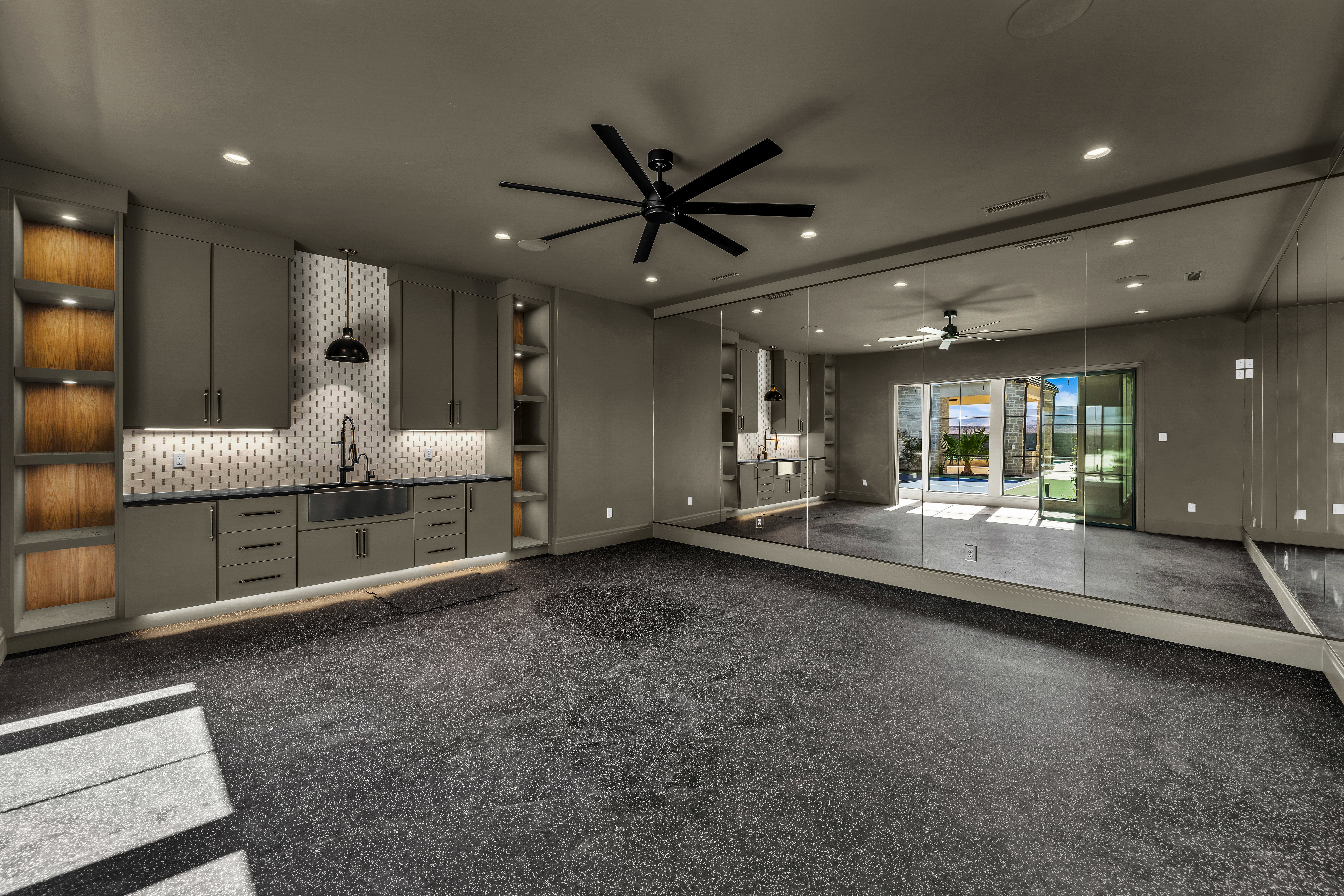 Spacious multi-purpose room featuring a built-in wet bar, full-height wall mirrors, recessed lighting, and a ceiling fan