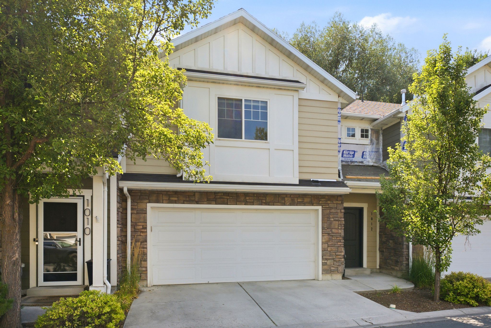 Contemporary townhome exterior featuring a two-car garage, stone veneer siding, and a gabled roofline