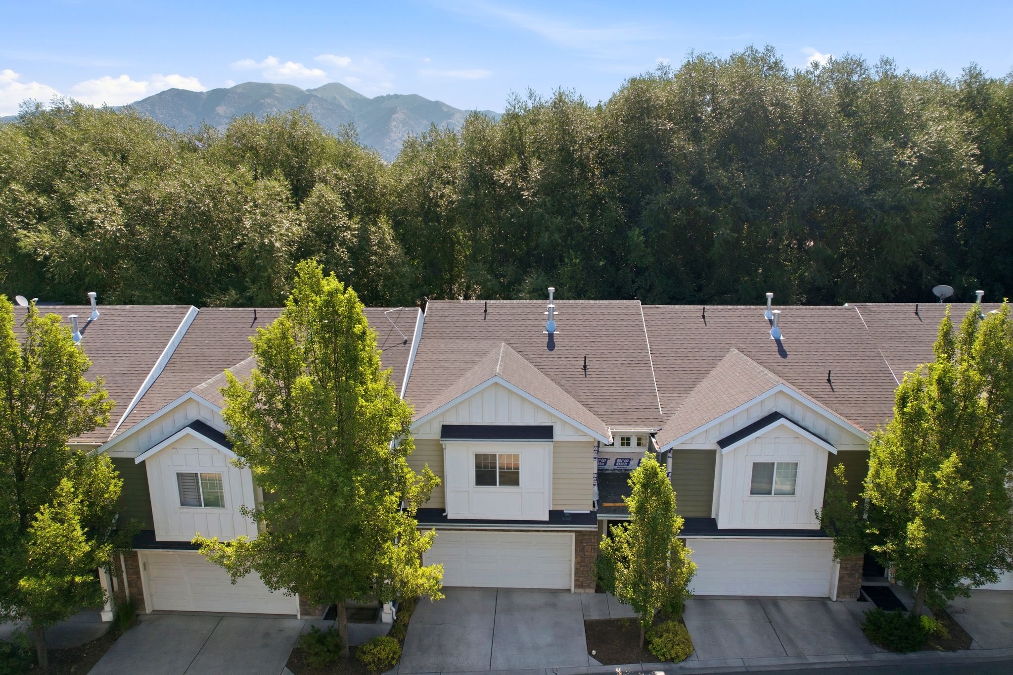 Contemporary townhomes featuring attached garages, gabled rooflines, and a palette of light-toned siding