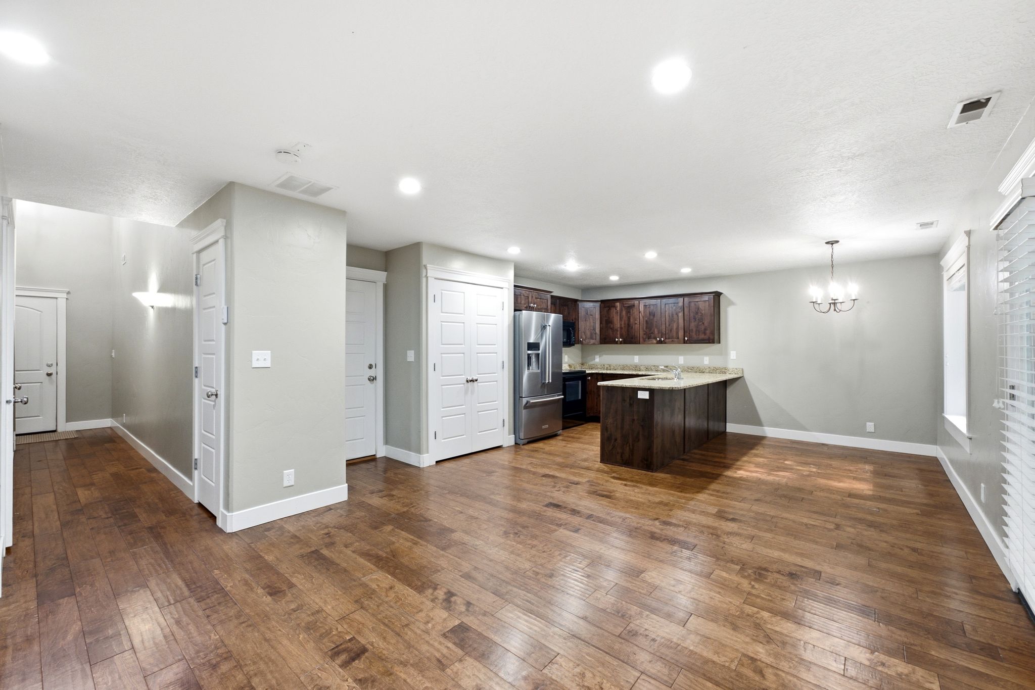 Expansive living area featuring warm wood-finish flooring, recessed lighting, and a neutral wall palette