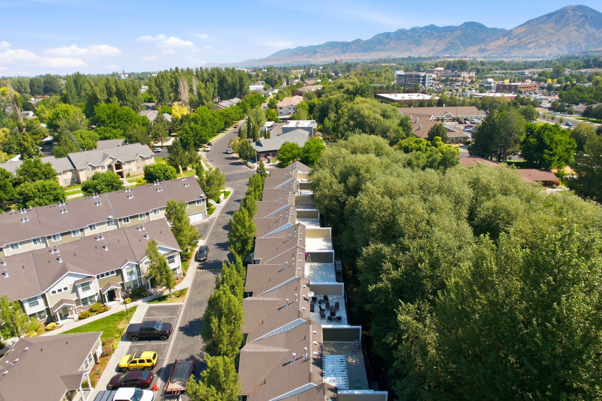 Aerial perspective showcasing a community of multi-story residences with brown roofs and light-toned siding
