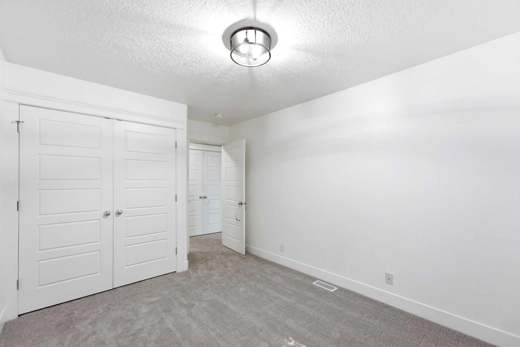 Bright interior space featuring light gray carpeting, light grey walls, and a contemporary semi-flush ceiling fixture