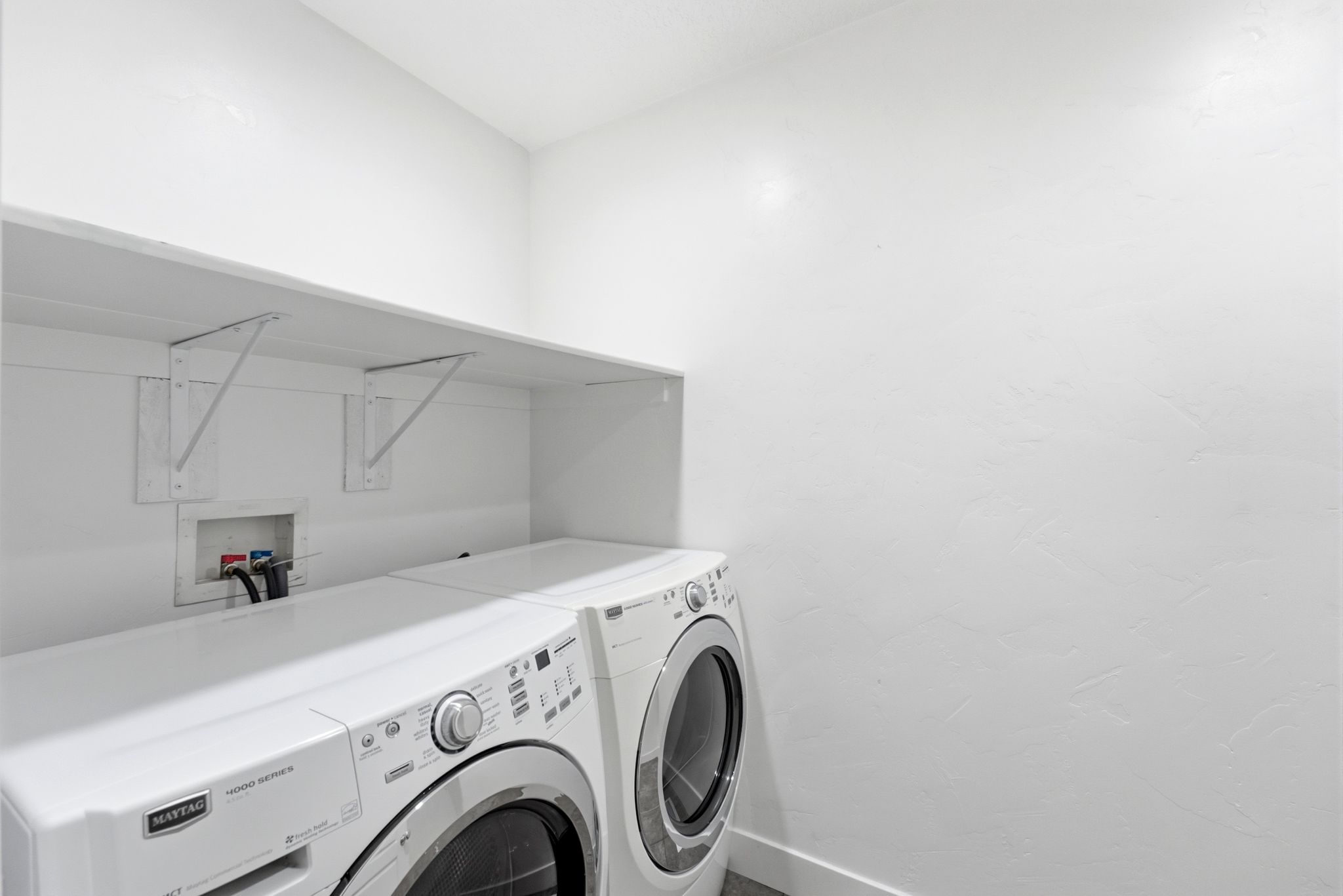 Dedicated laundry area featuring a wall-mounted shelf, appliance hookups, and light-colored walls