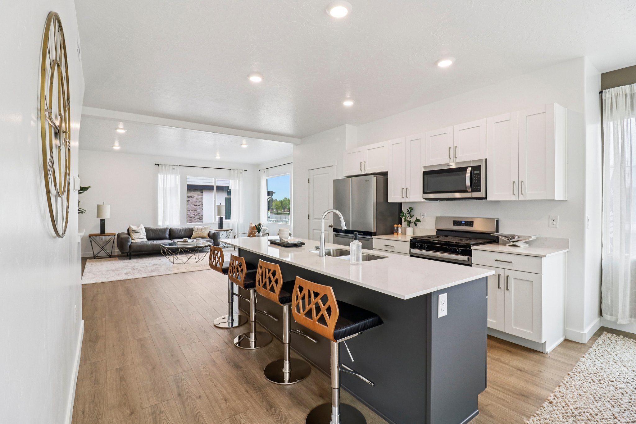 Contemporary kitchen featuring white cabinetry, stainless steel appliances, and a dark-toned island with seating