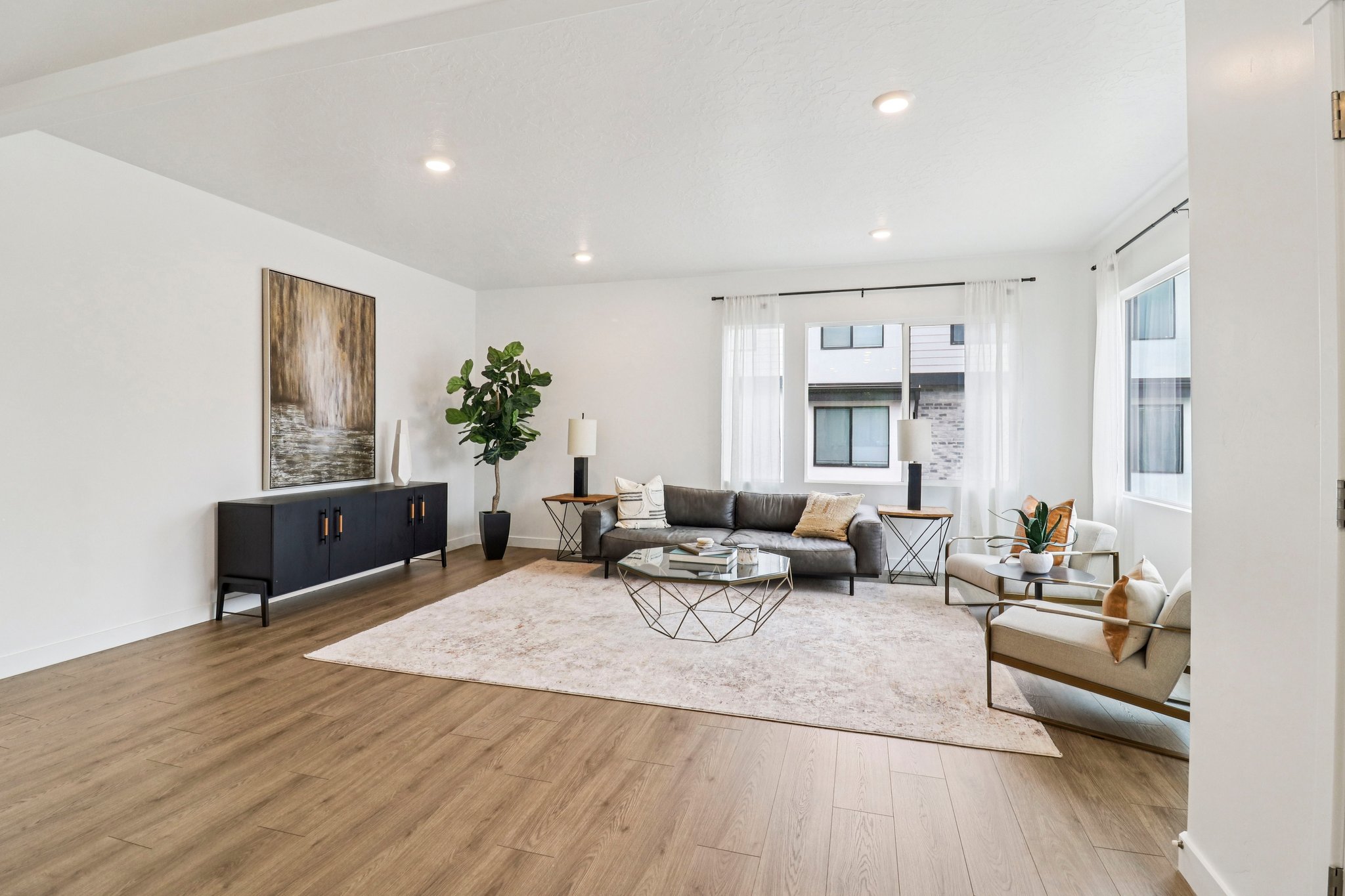 Spacious living area featuring wood-finish flooring, recessed lighting, and multiple windows with white drapery