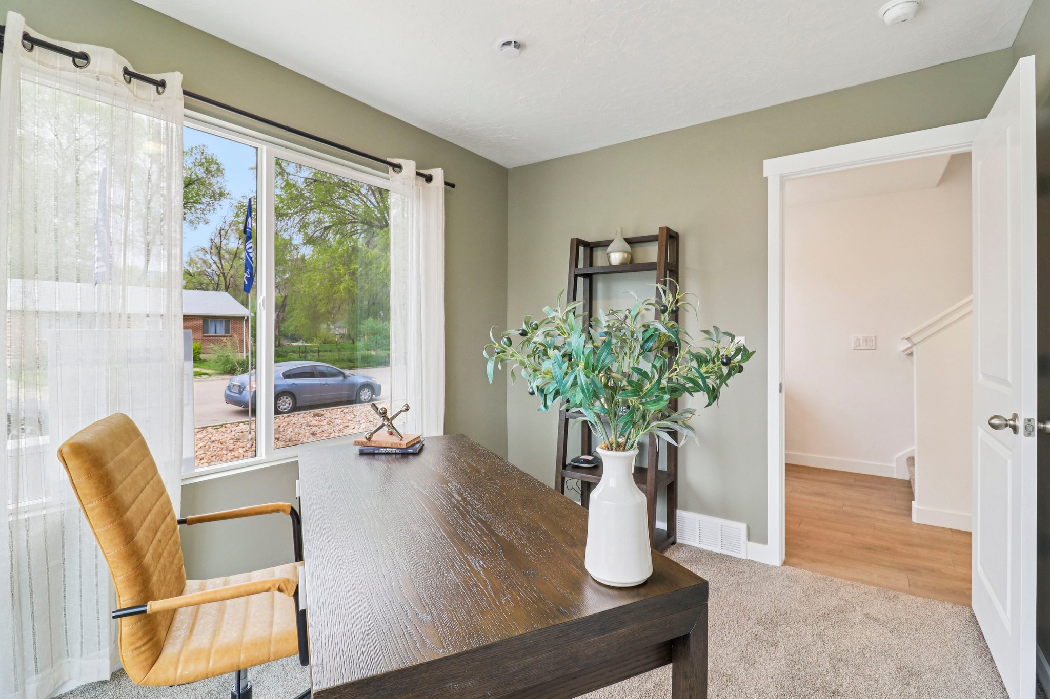 Spacious room featuring a large window, soft carpeting, and neutral wall tones