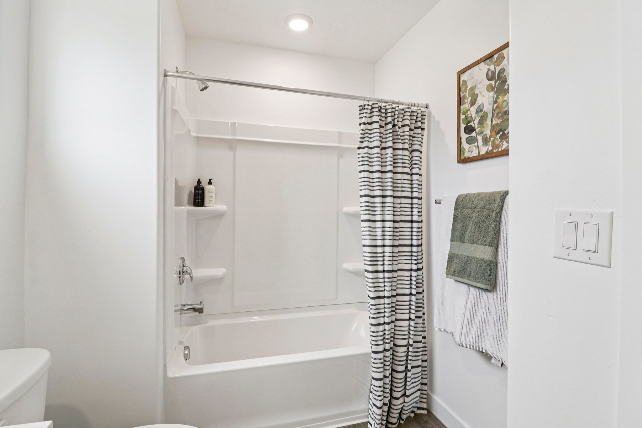 White shower/tub combination featuring integrated shelving and a chrome showerhead