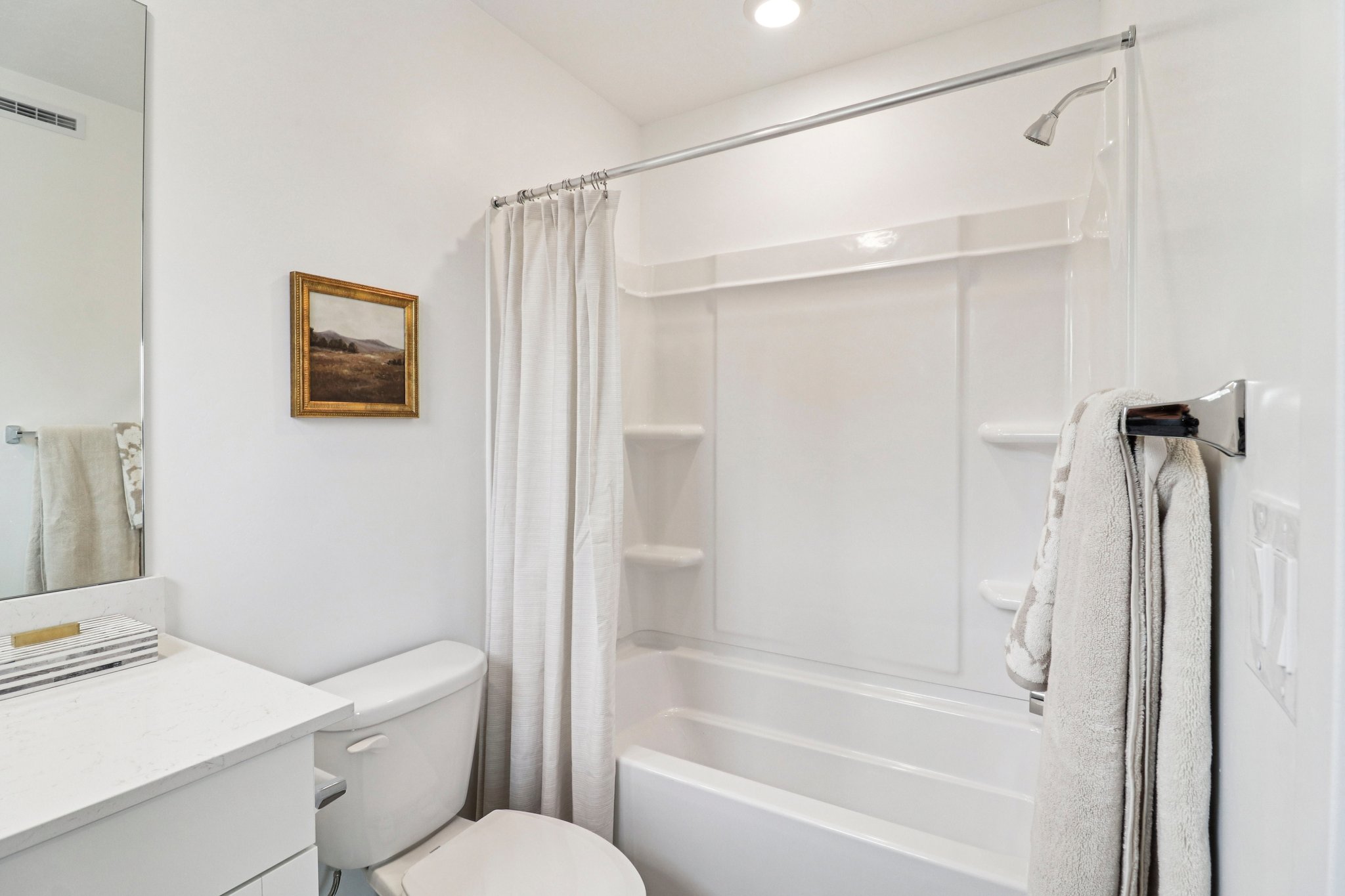 Bathroom featuring a white shower/tub combination with integrated shelving, a chrome showerhead, and a chrome towel bar