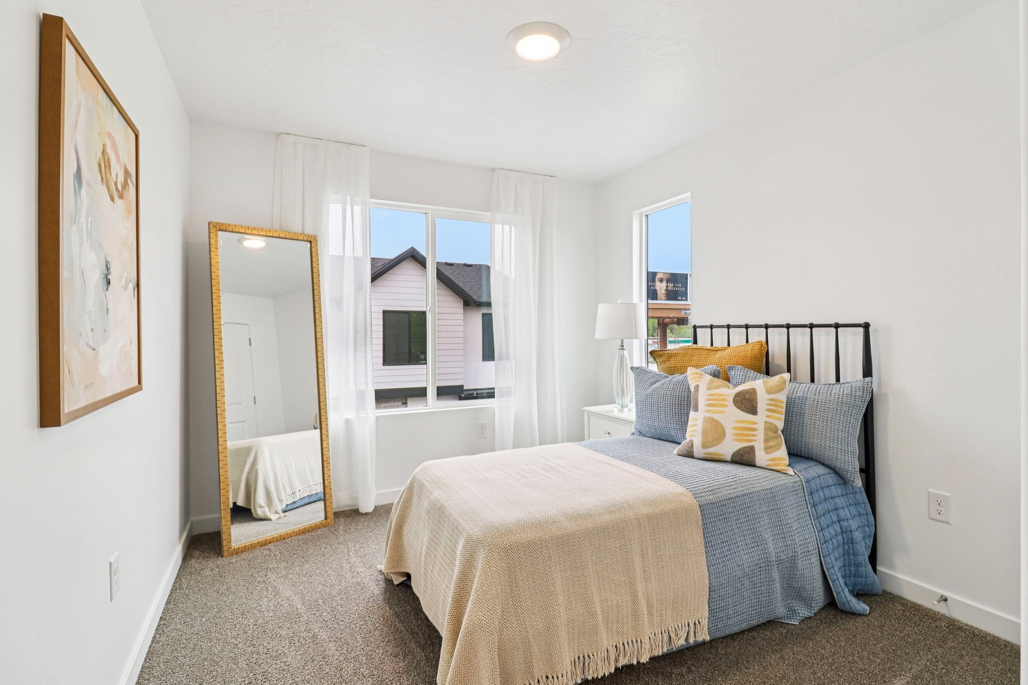 Bright room featuring a large window, a smaller secondary window, light-colored walls, and textured carpeting